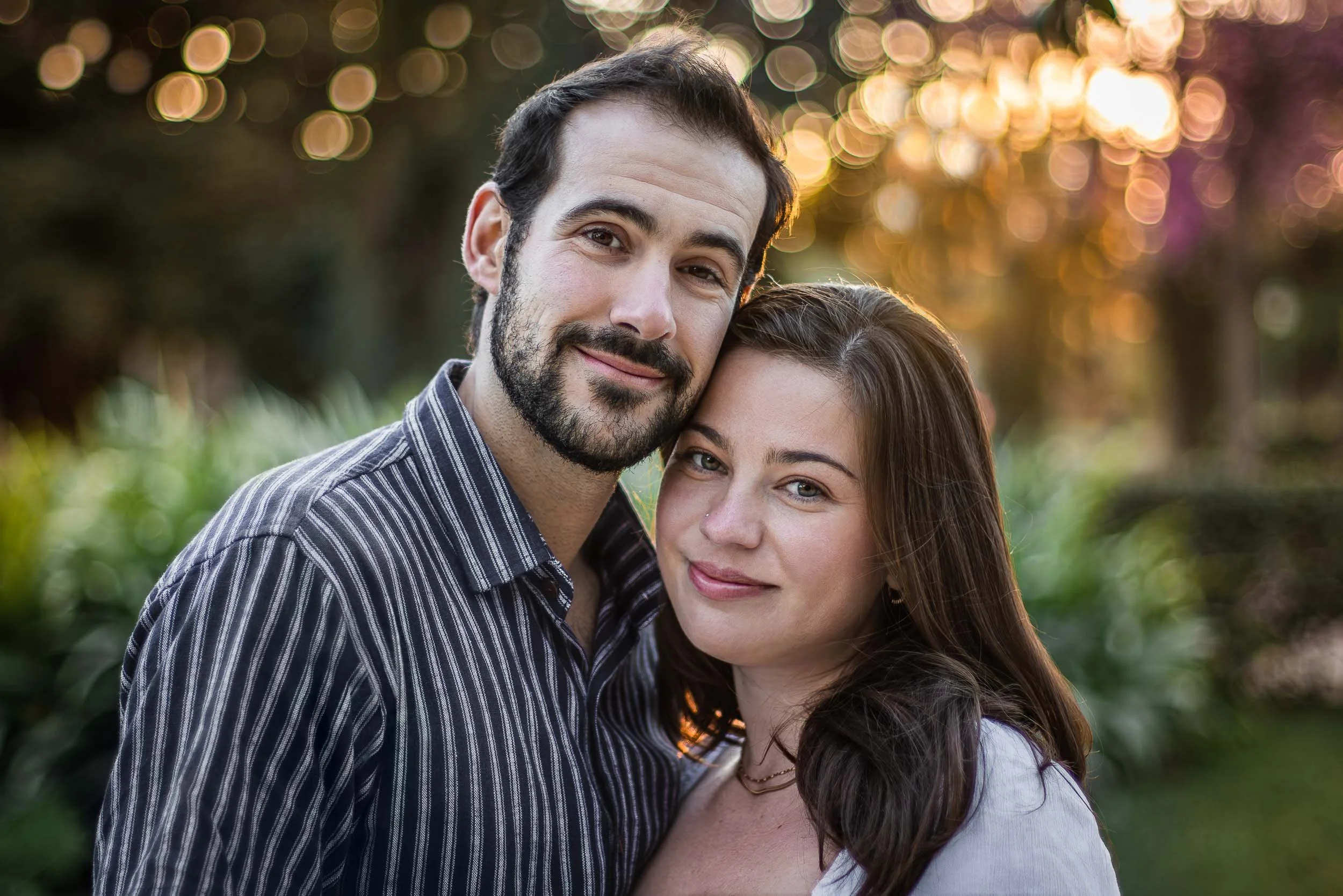 Close portrait of a couple standing together and looking toward the camera in warm evening light