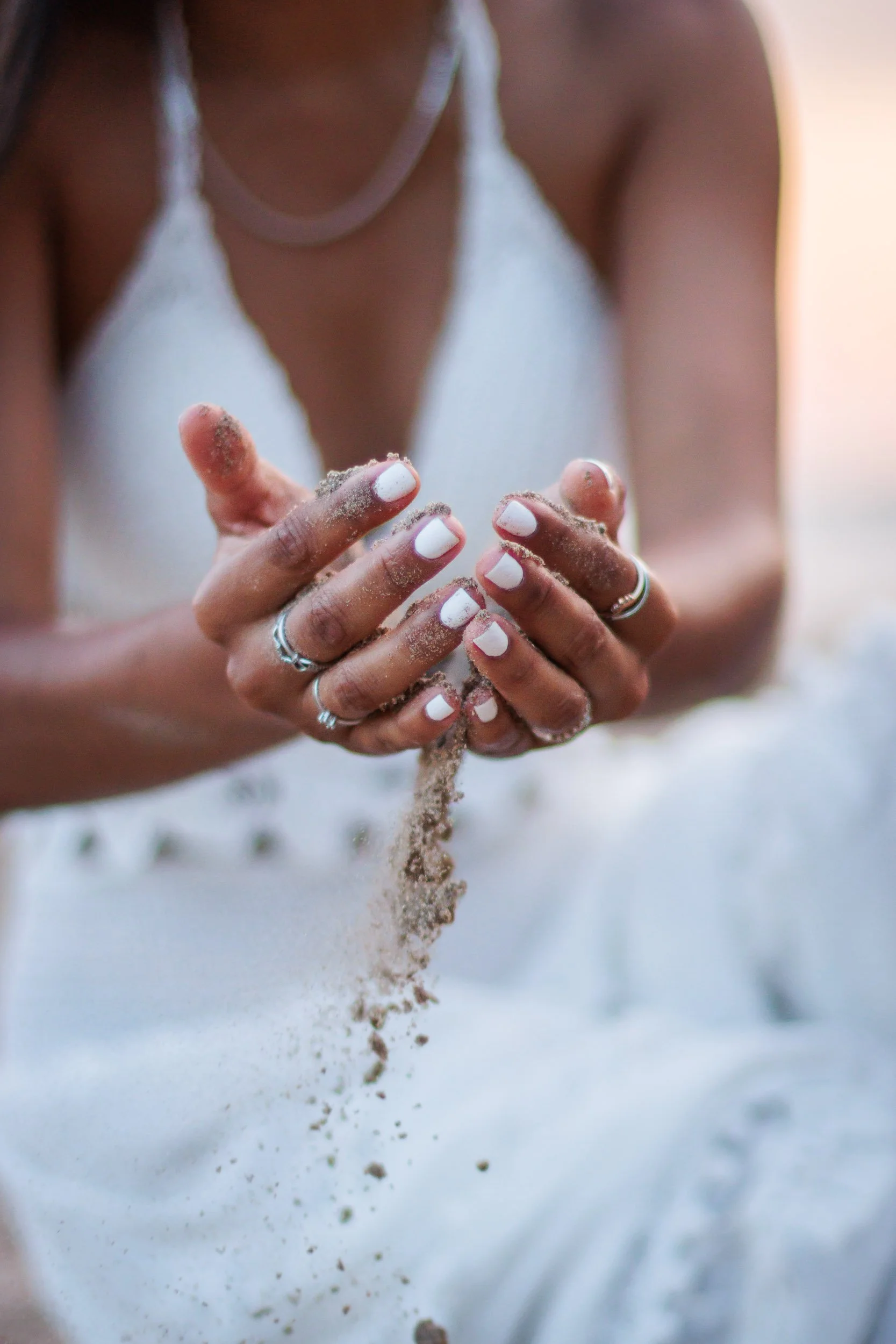 Close-up detail of hands holding sand during a beach portrait session