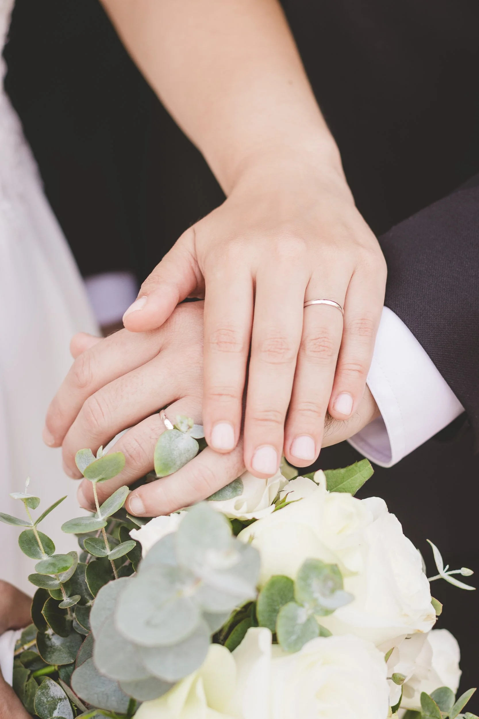Close-up of the couple's hands with wedding rings resting on the bouquet