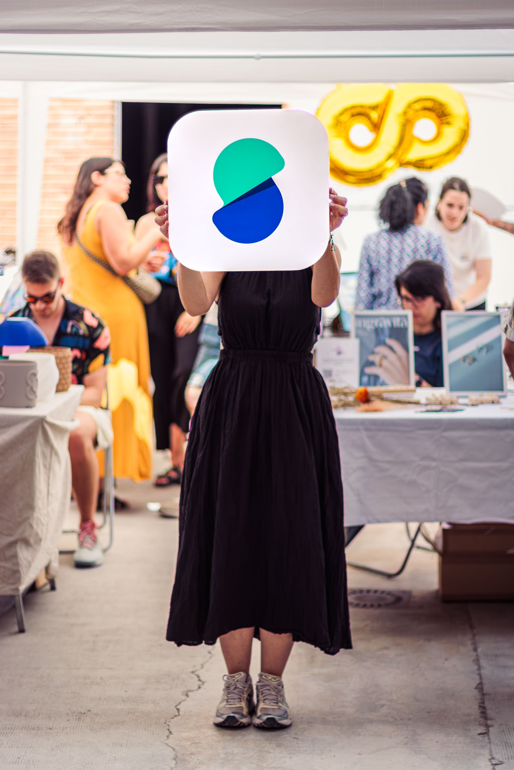 Event organizer holding a large branded sign in front of vendor booths during a brand activation event