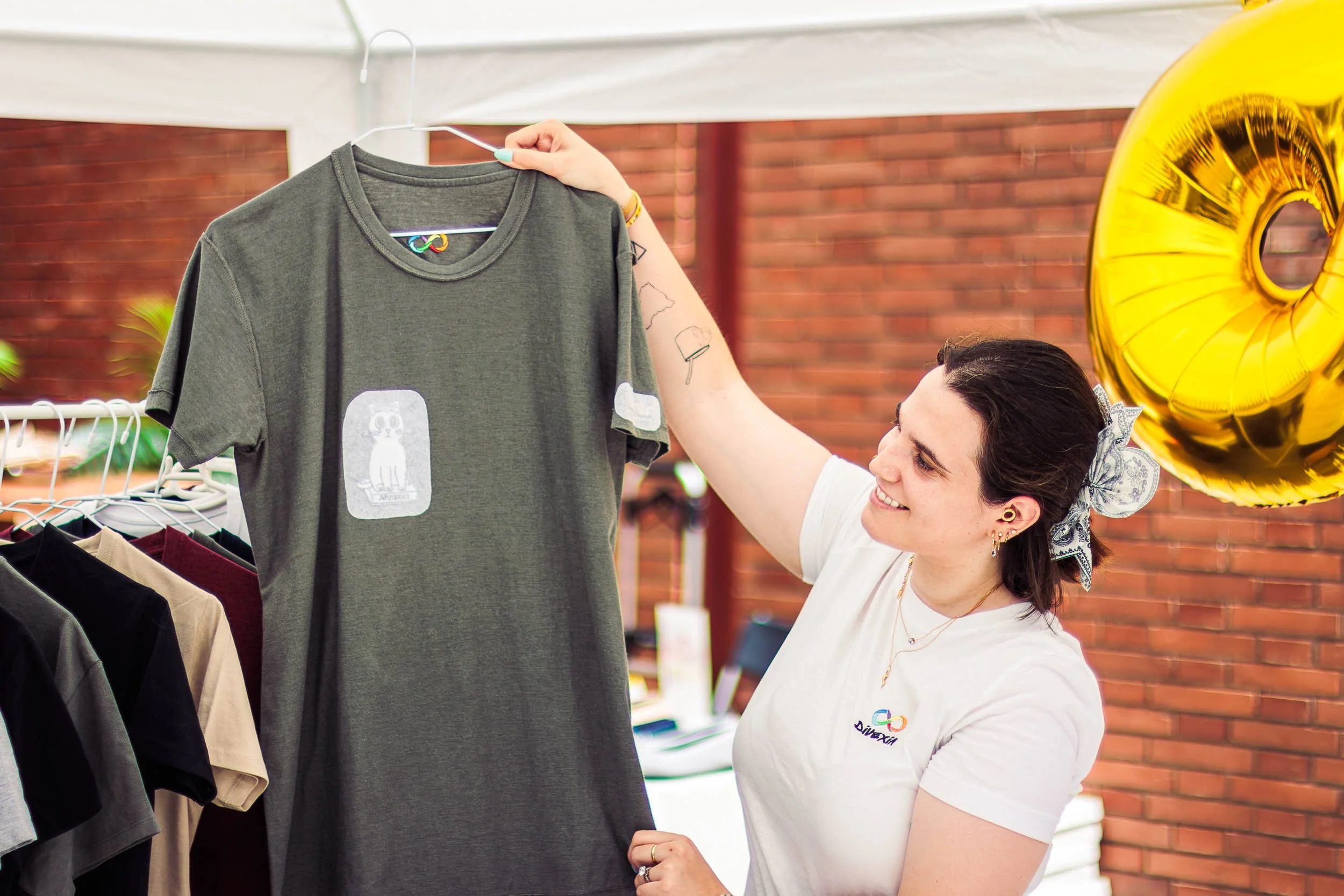 Vendor holding up a T-shirt at a clothing stand during the event