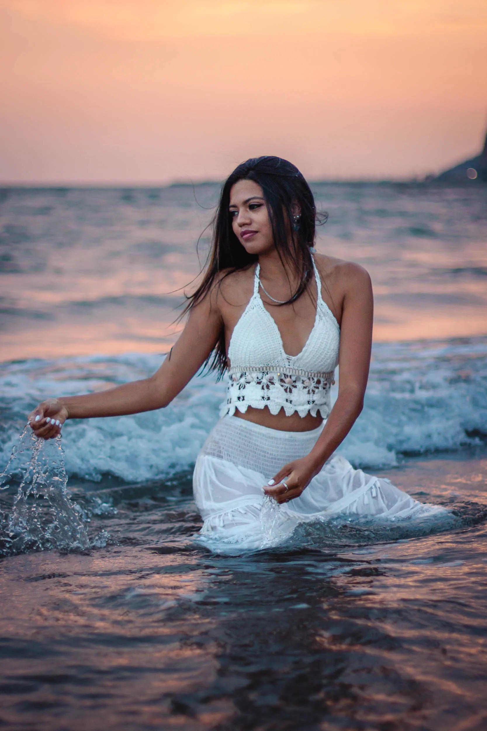 Portrait of a woman standing in the sea in a white dress at sunset
