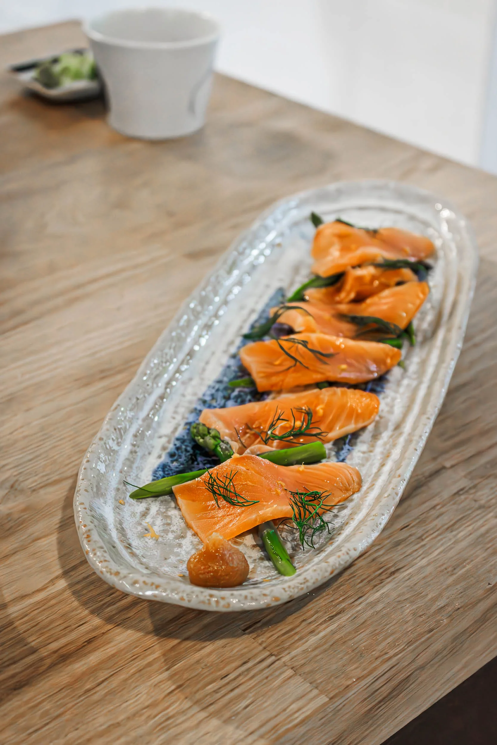 Food photography of sliced fish and green garnish on a wooden table