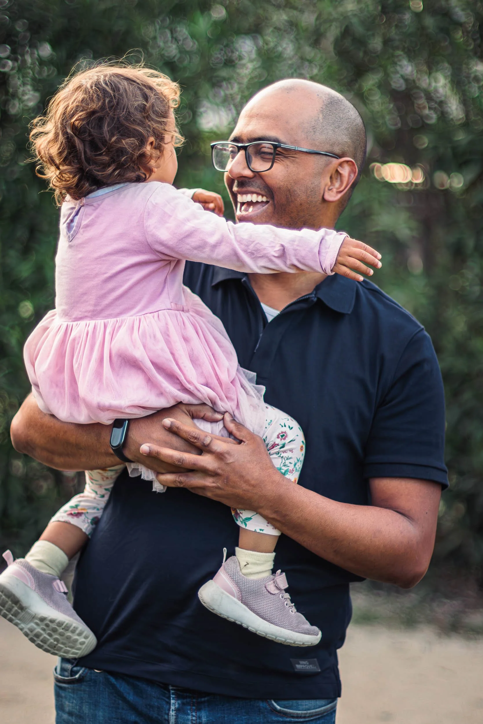 Portrait of a father holding his daughter and smiling during an outdoor family session