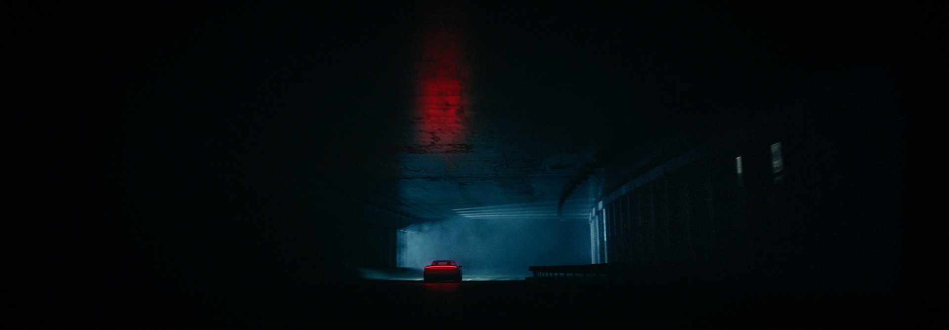 A Porsche Taycan driving in a dark tunnel.