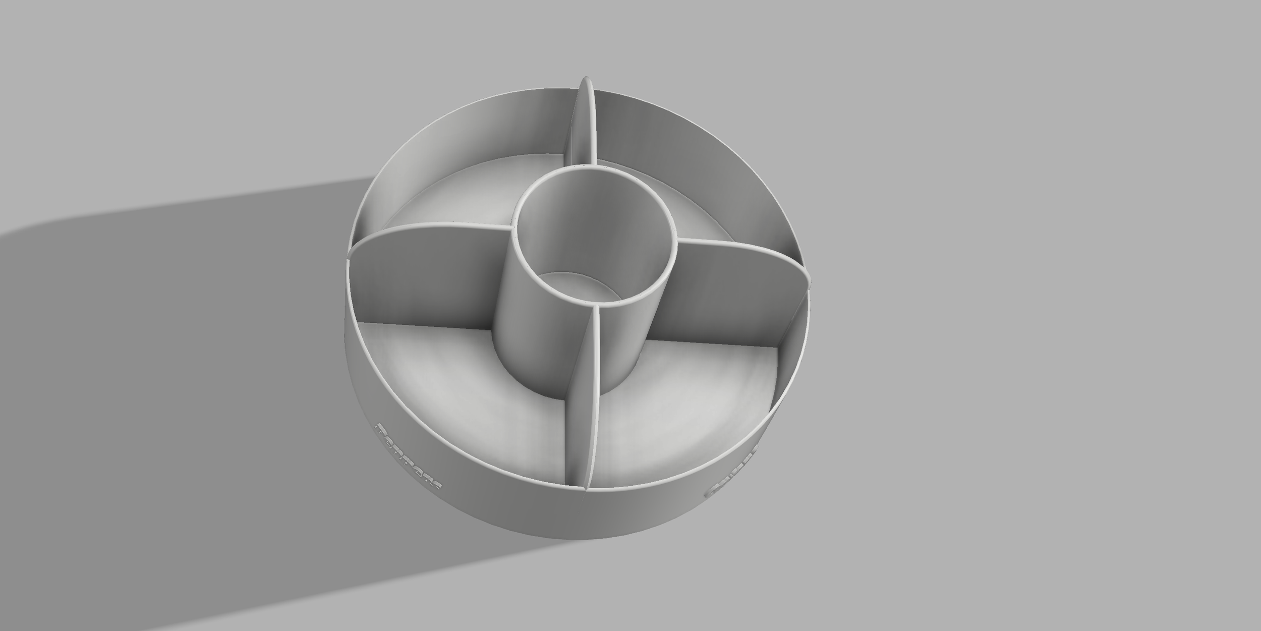 A circular multi-compartment organizer with a central hollow section and five separate compartments around it, placed on a grey surface.