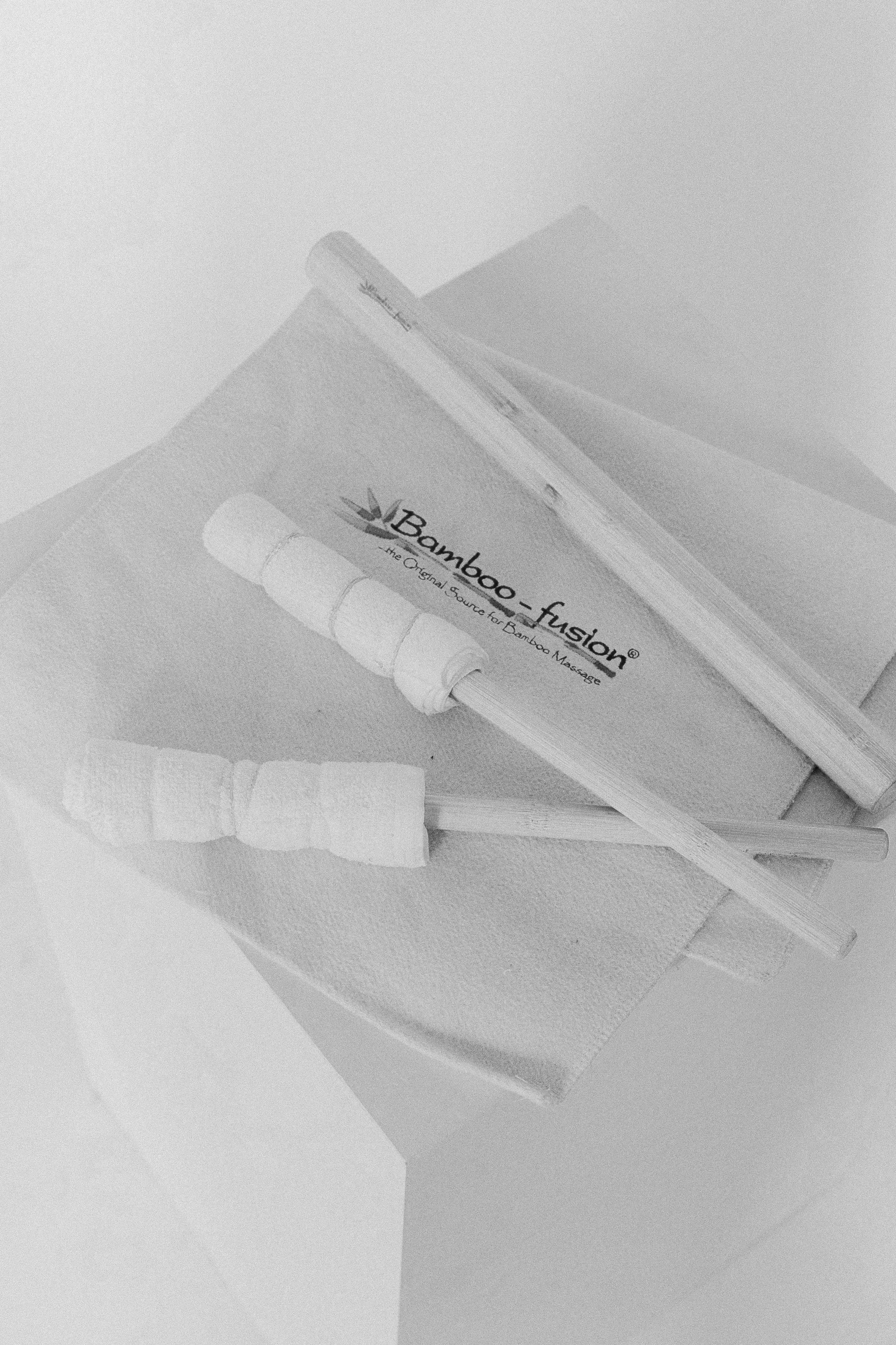 A box of Bamboo-Fusion, the original sound for bamboo massage, with a massage stick and a cloth next to it.