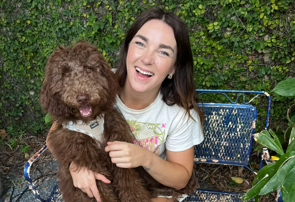 Megan Aulie, BCBA sitting with brown doodle dog