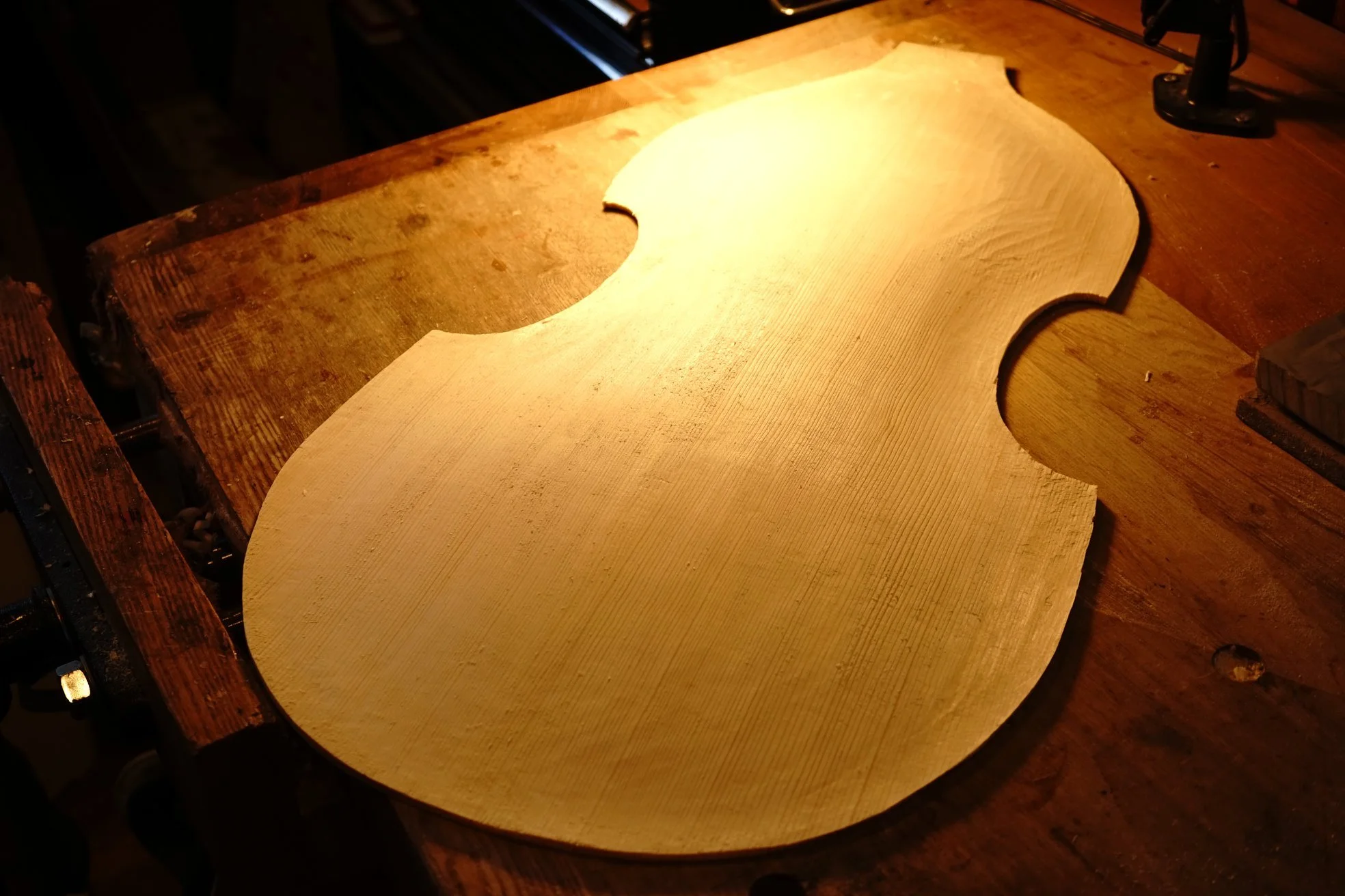 丸みを帯びた特定の形をした木材の張り板が木製の作業台に置かれている写真