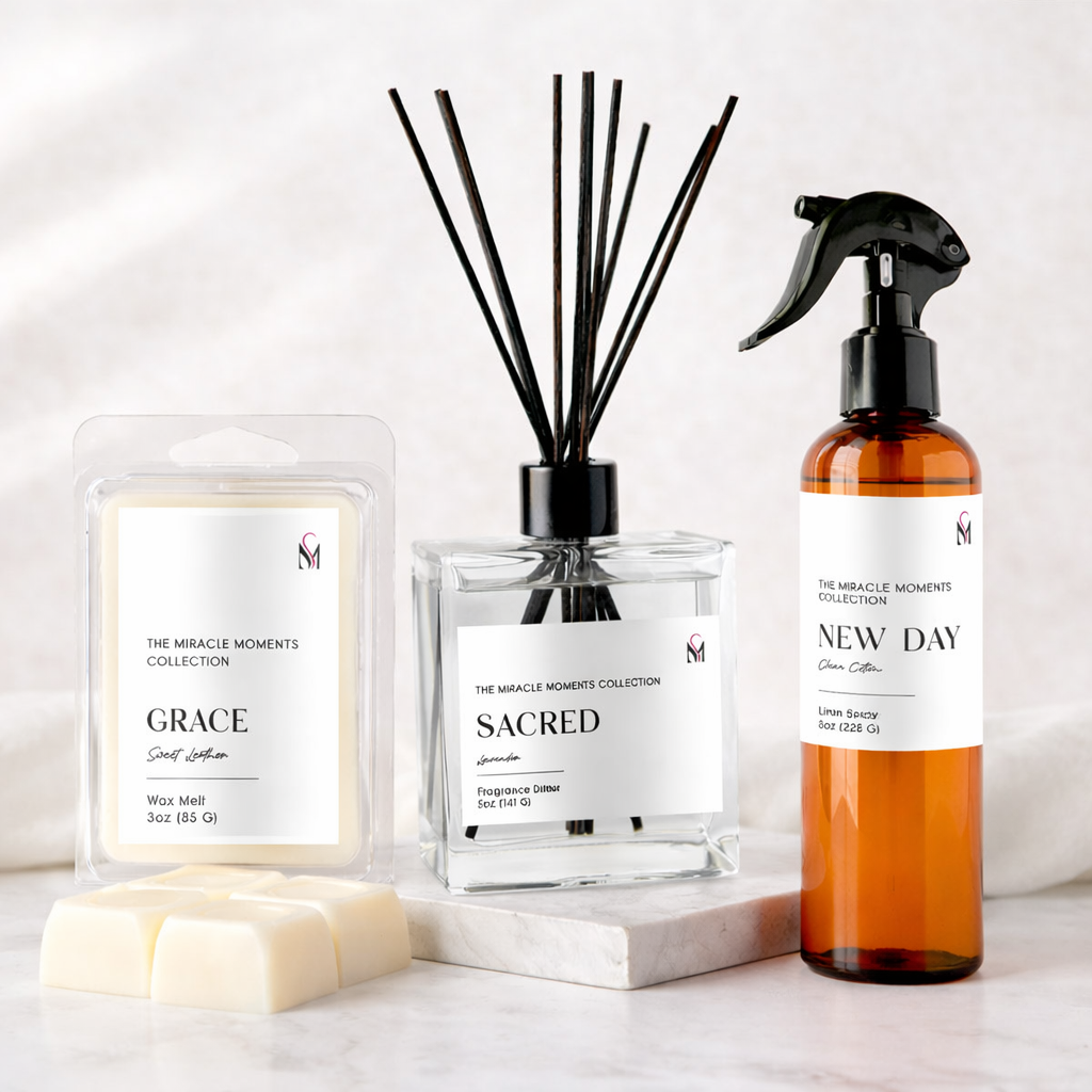 A collection of home fragrance products including a wax melt, reed diffuser, and room spray labeled from The Miracle Moments Collection with scents named Grace, Sacred, and New Day.