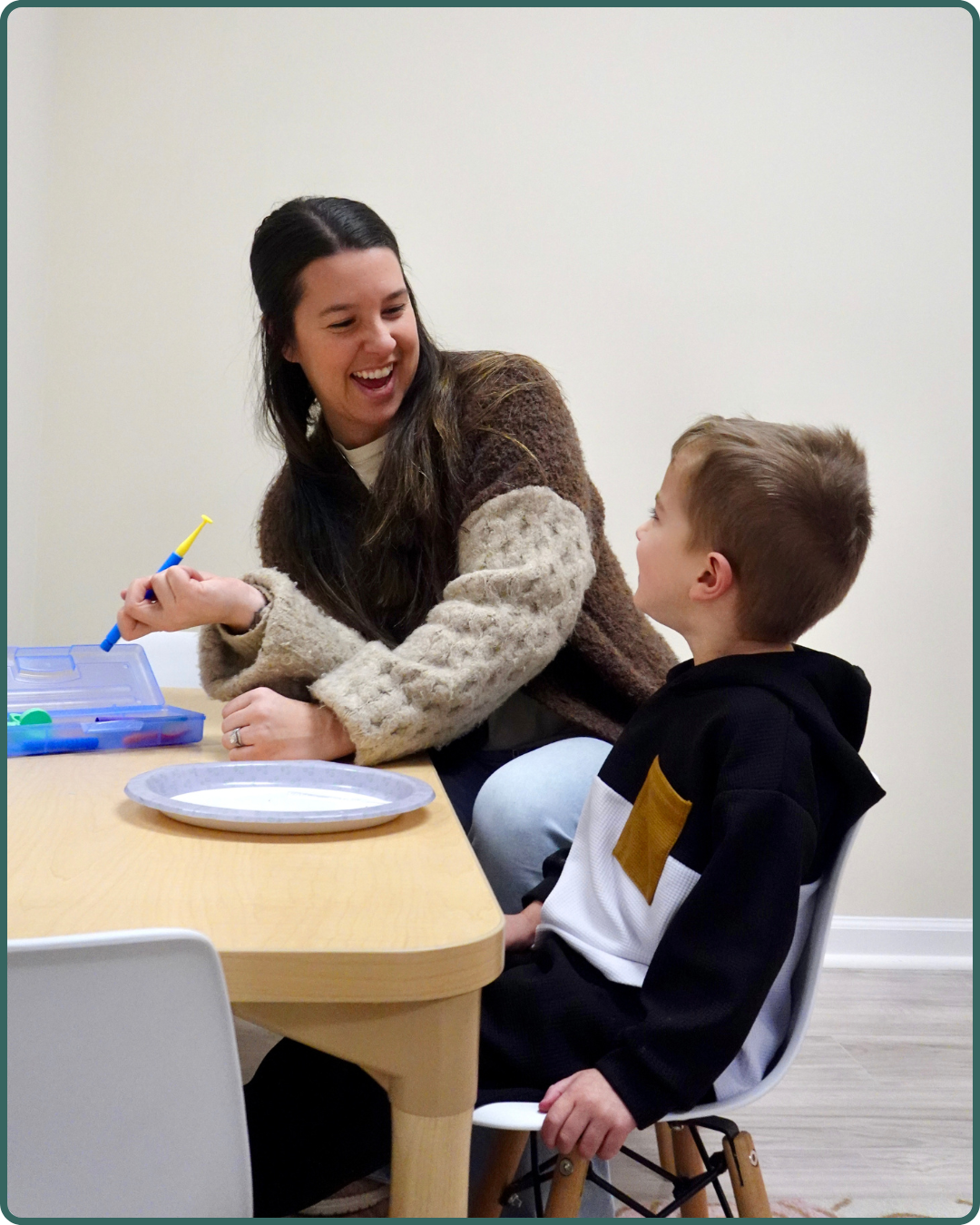 A young boy in a sweatshirt receiving pediatric therapy services at The Therapy Hub in Manahawkin, NJ with a provider.