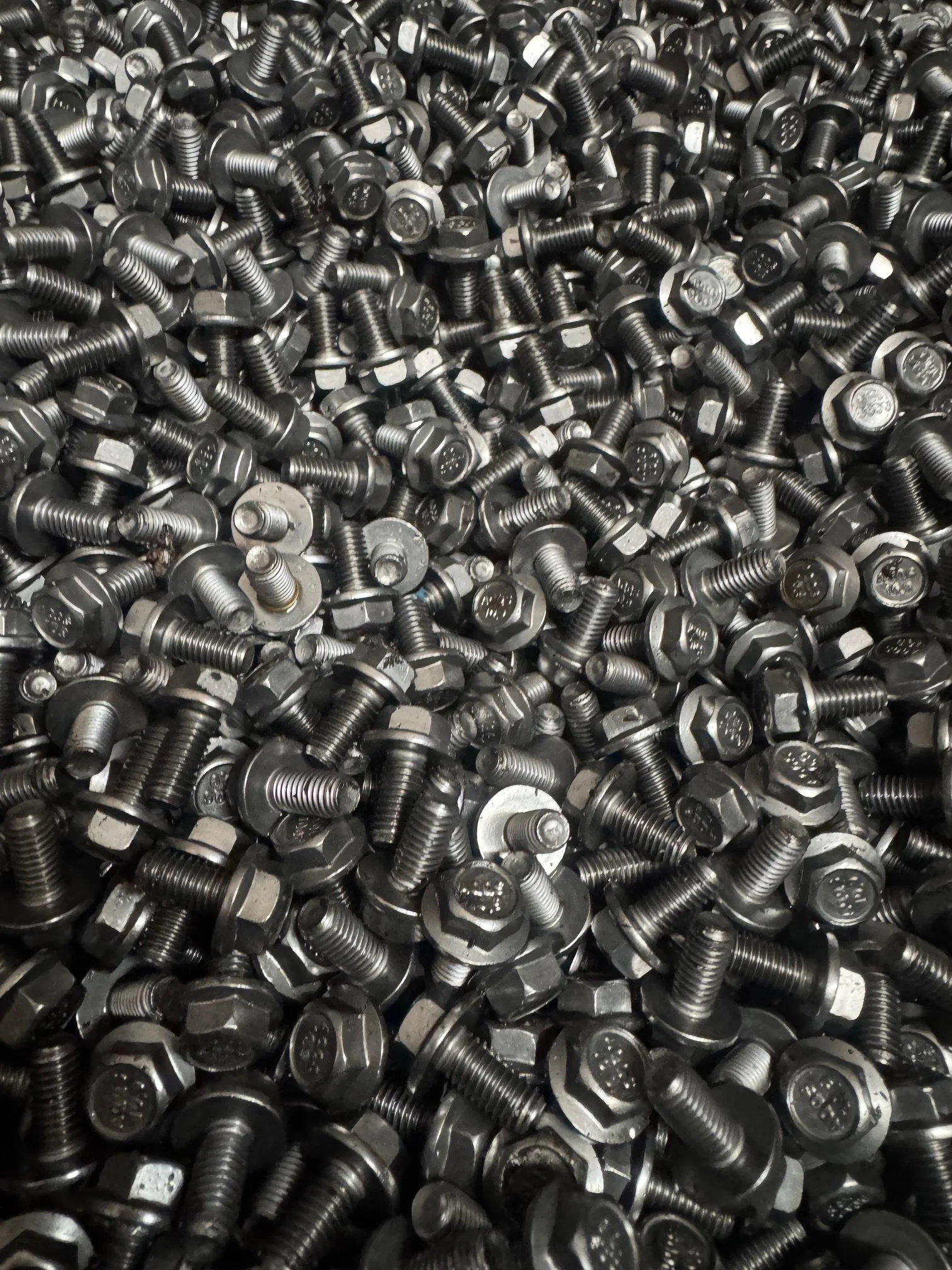 A large pile of metal bolts with hexagonal heads and threaded shafts.