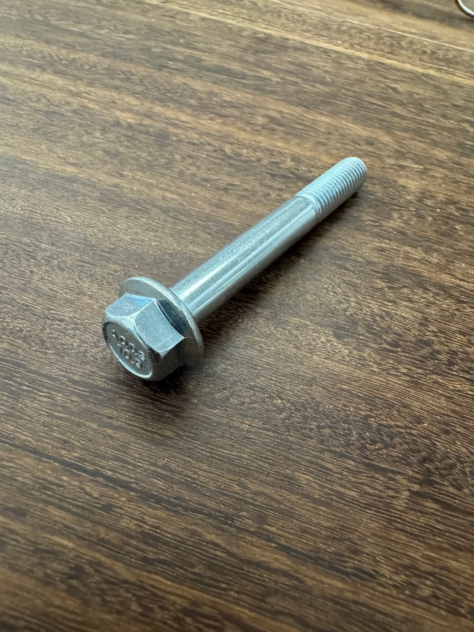 Metal bolt with a hexagonal head lying on a wooden surface.
