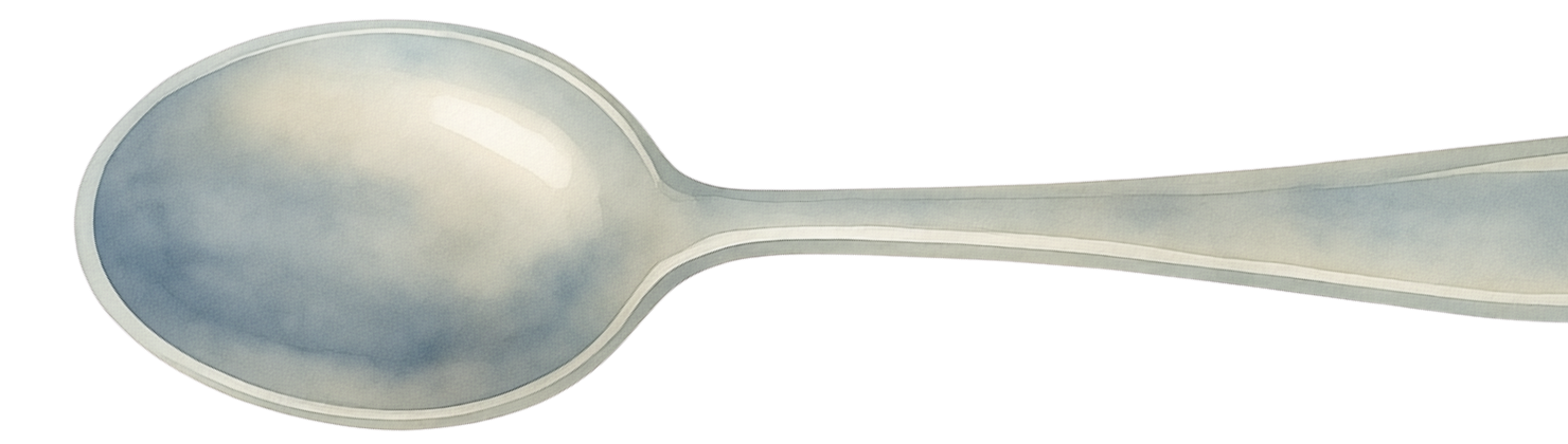 A metal spoon lying flat on a surface with the bowl positioned on the left and handle extending to the right.