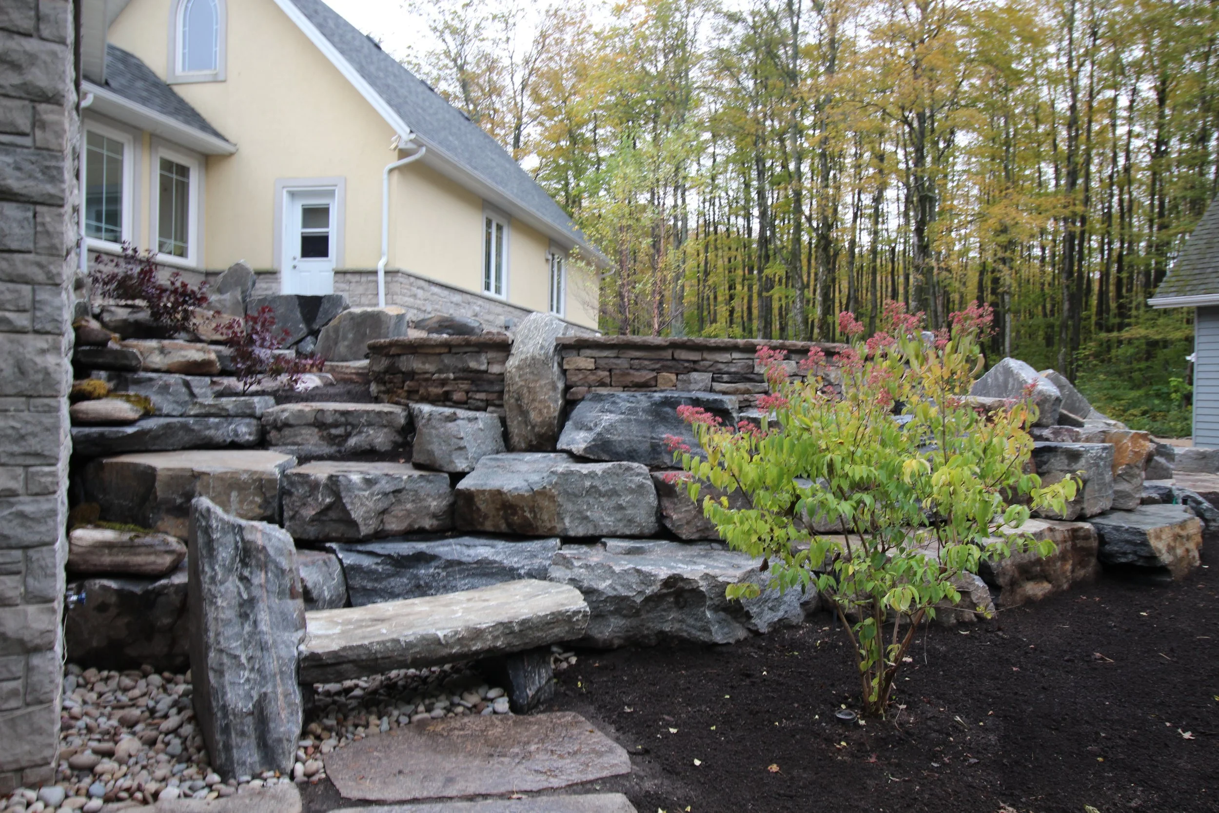drystone wall perched up on a naturalized granite armourstone outcropping