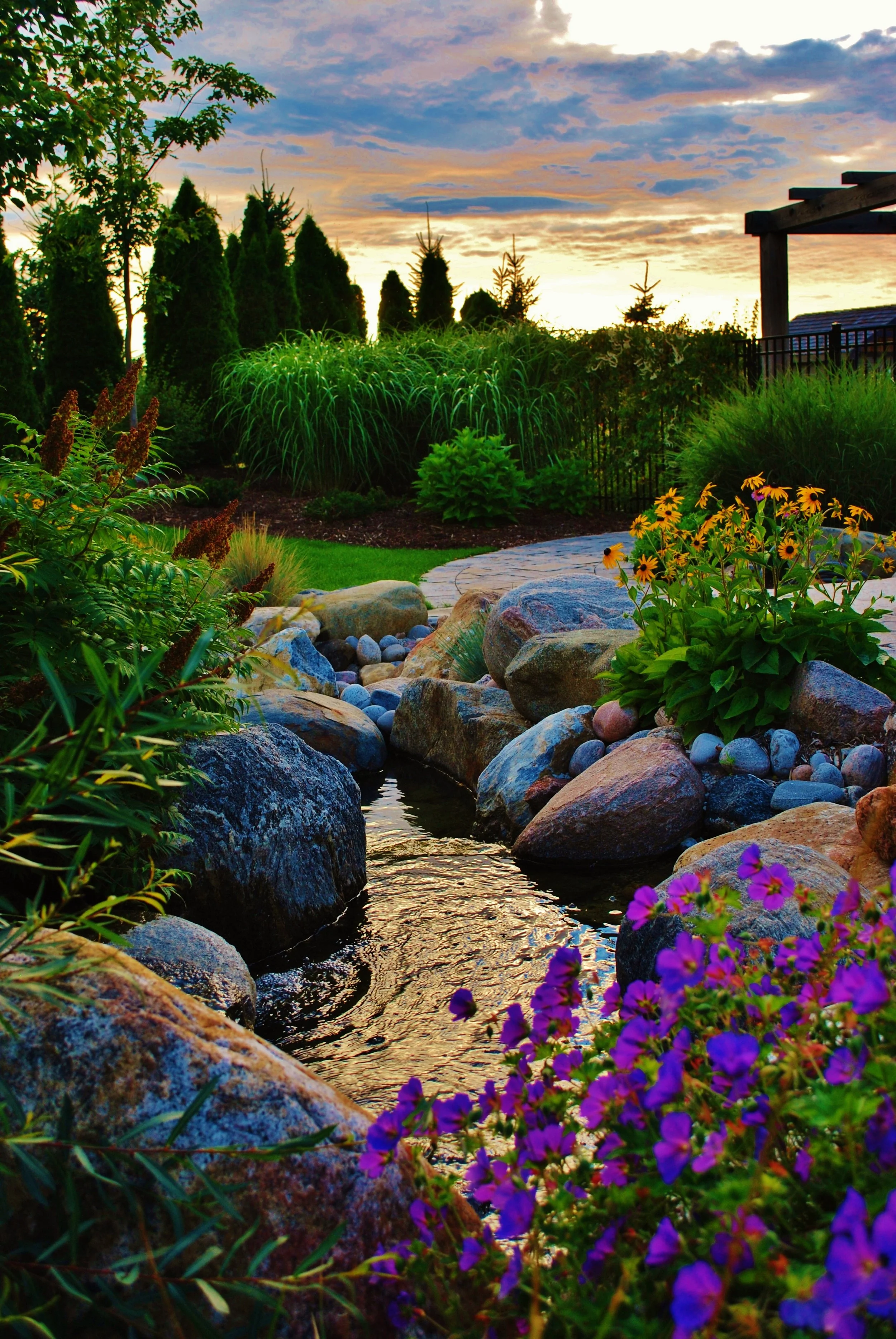 Lush gardens next to a stream at dusk