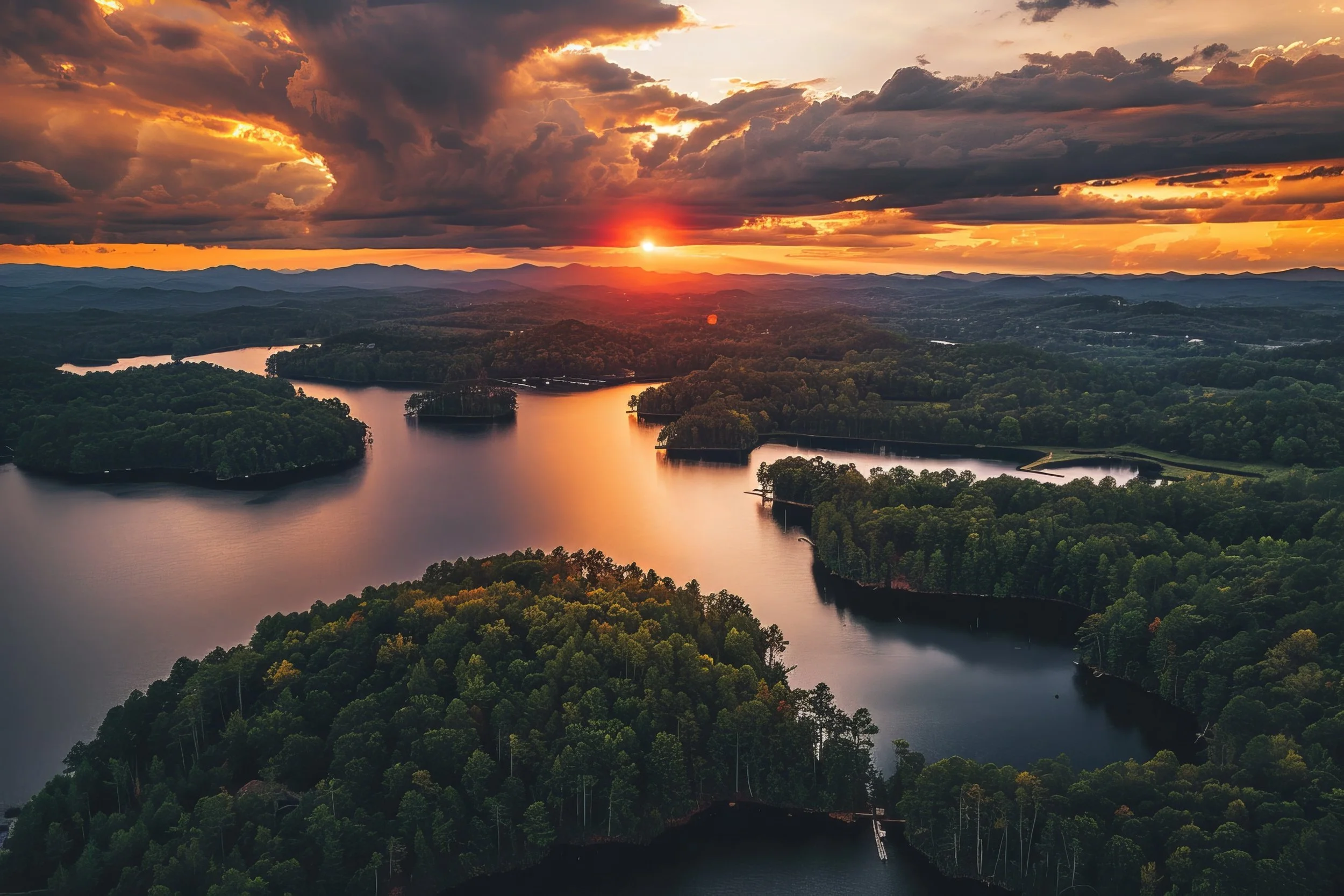 Aerial view of a winding river surrounded by dense forest with a sunset and dramatic clouds in the sky.