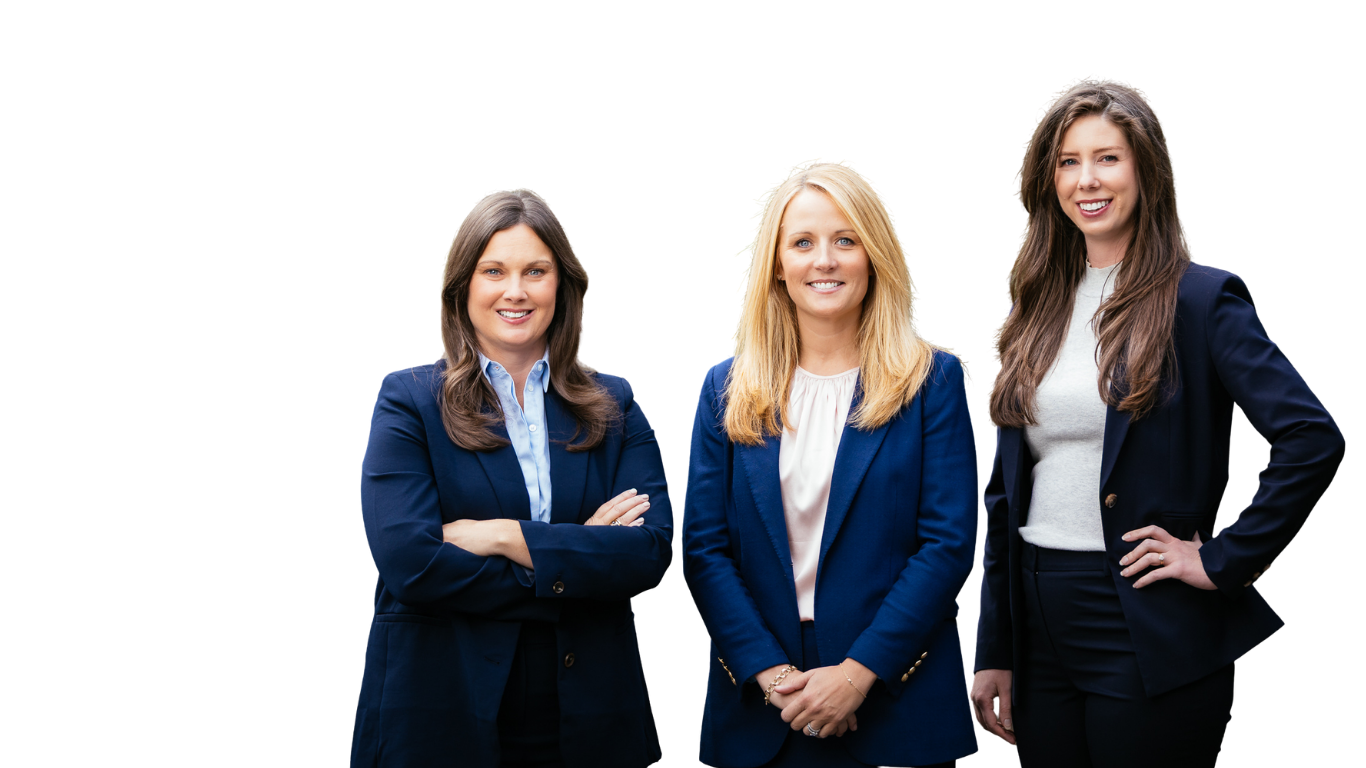 Three professional women posing together, dressed in business attire, smiling at the camera.