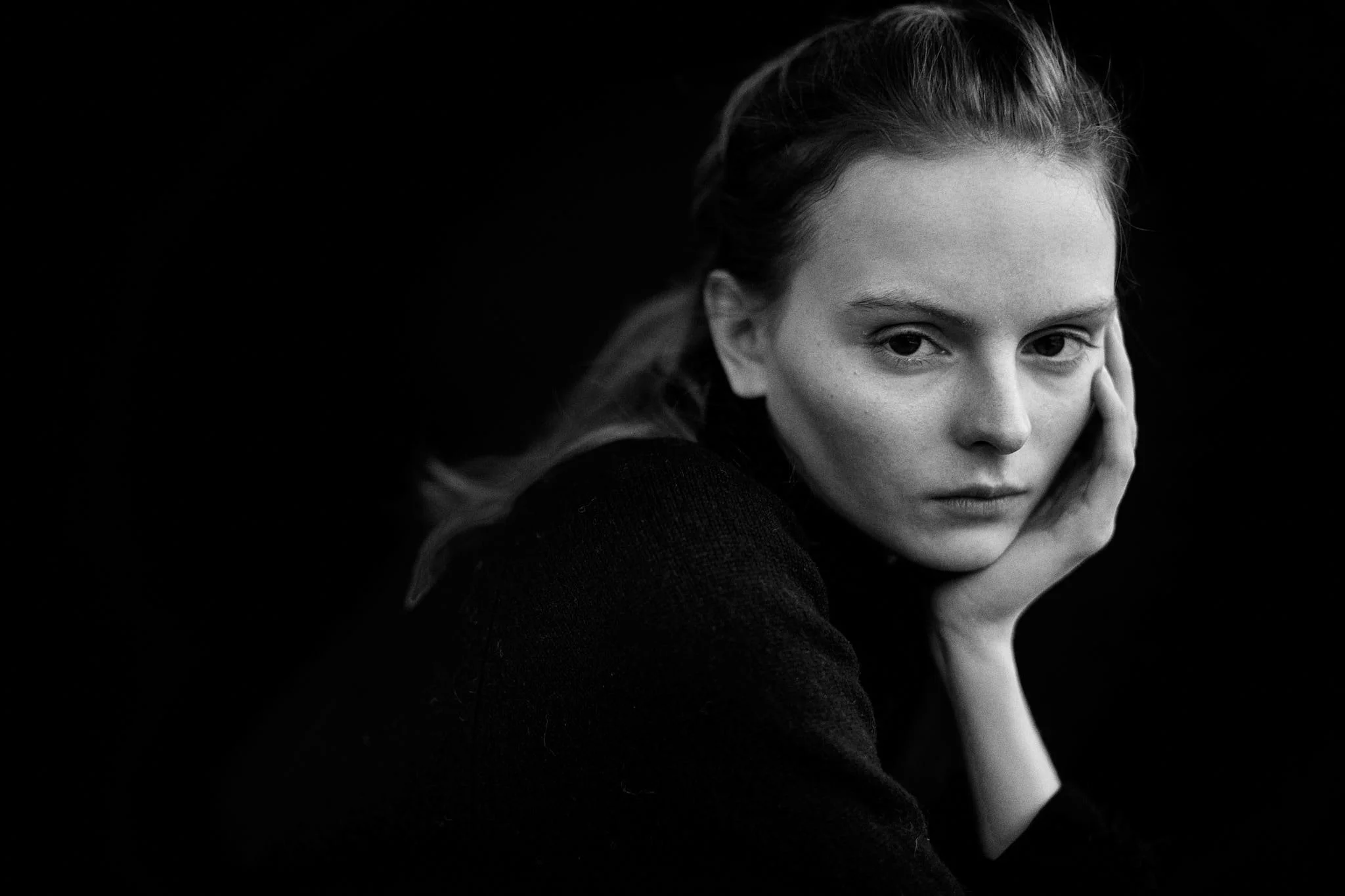 Black and white portrait of a young woman resting her chin on her hand, portrait photography by Oivind Haug