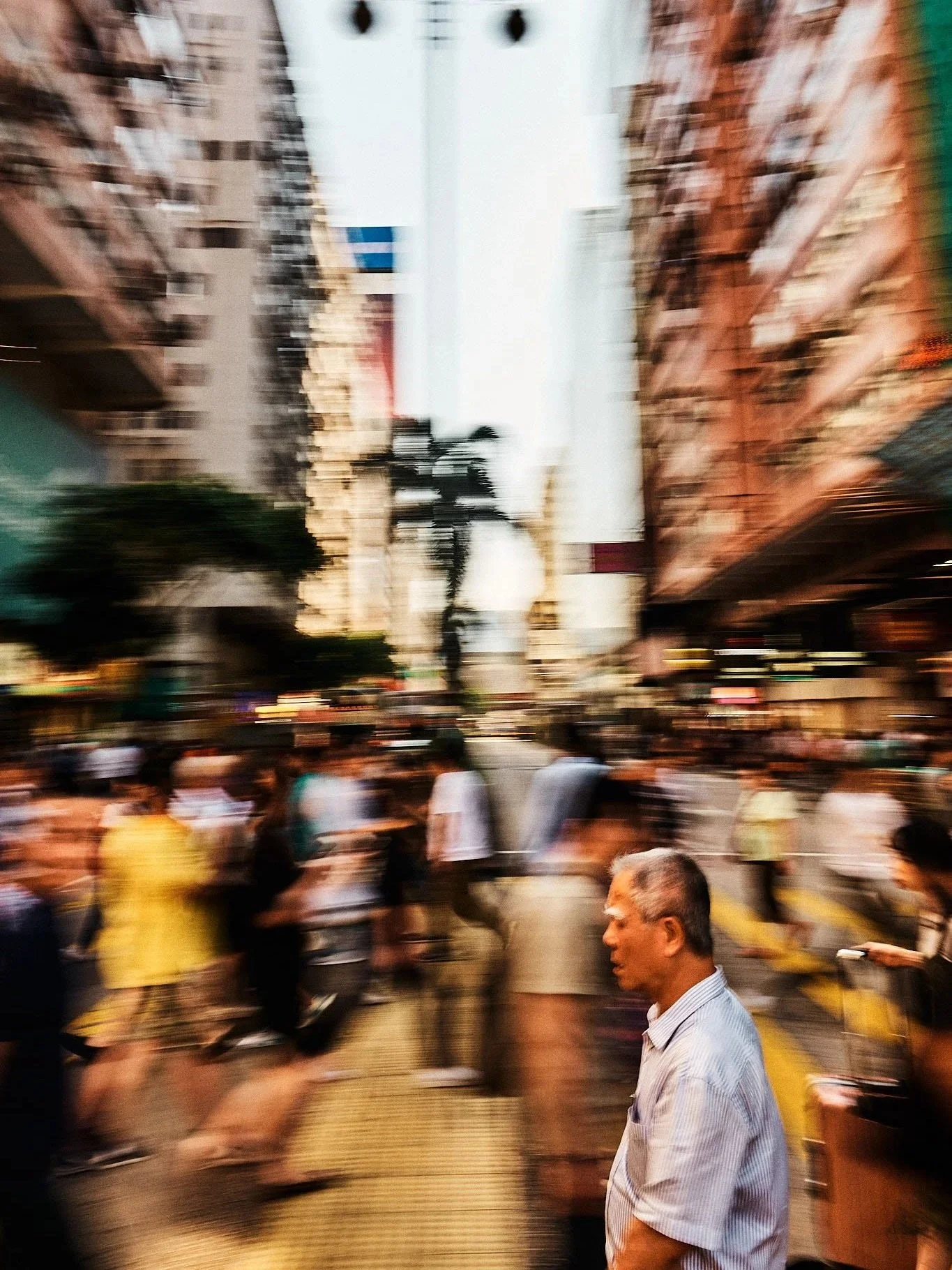 Blurred city street scene with people walking, tall buildings, and a palm tree in the background