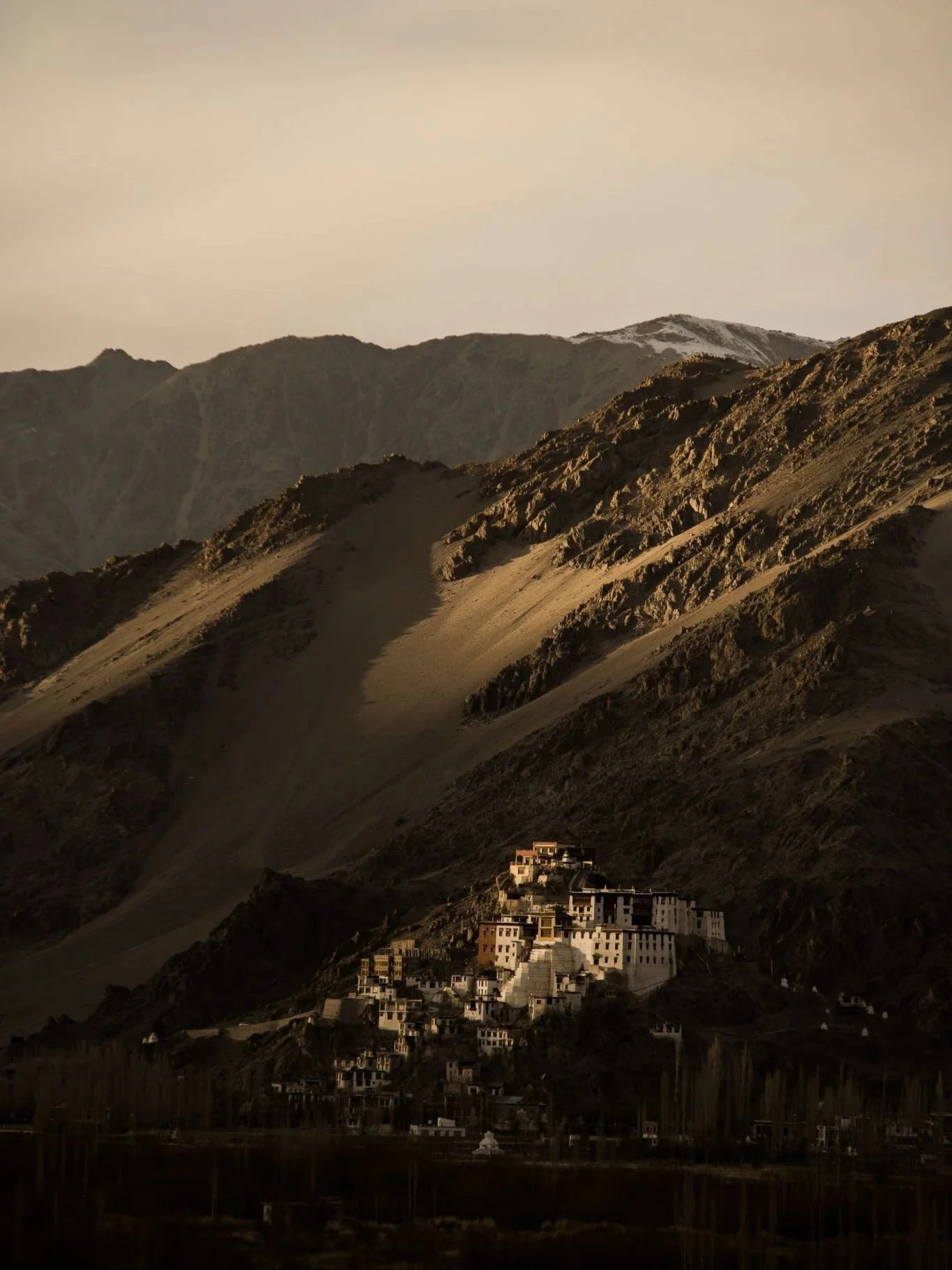 Mountain landscape with a small village or monastery nestled on a hillside.