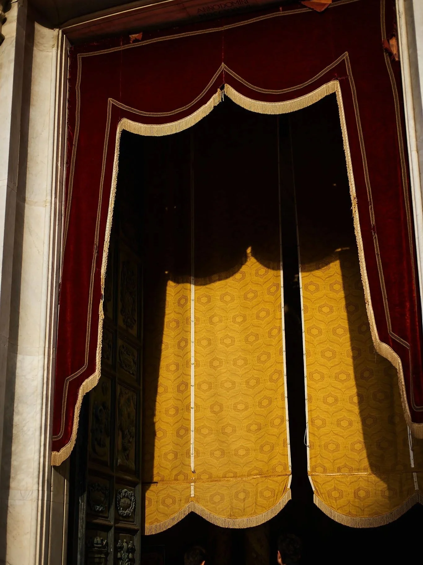 A decorative stage with red and yellow curtains, with the yellow curtain drawn back to reveal a dark backstage area.