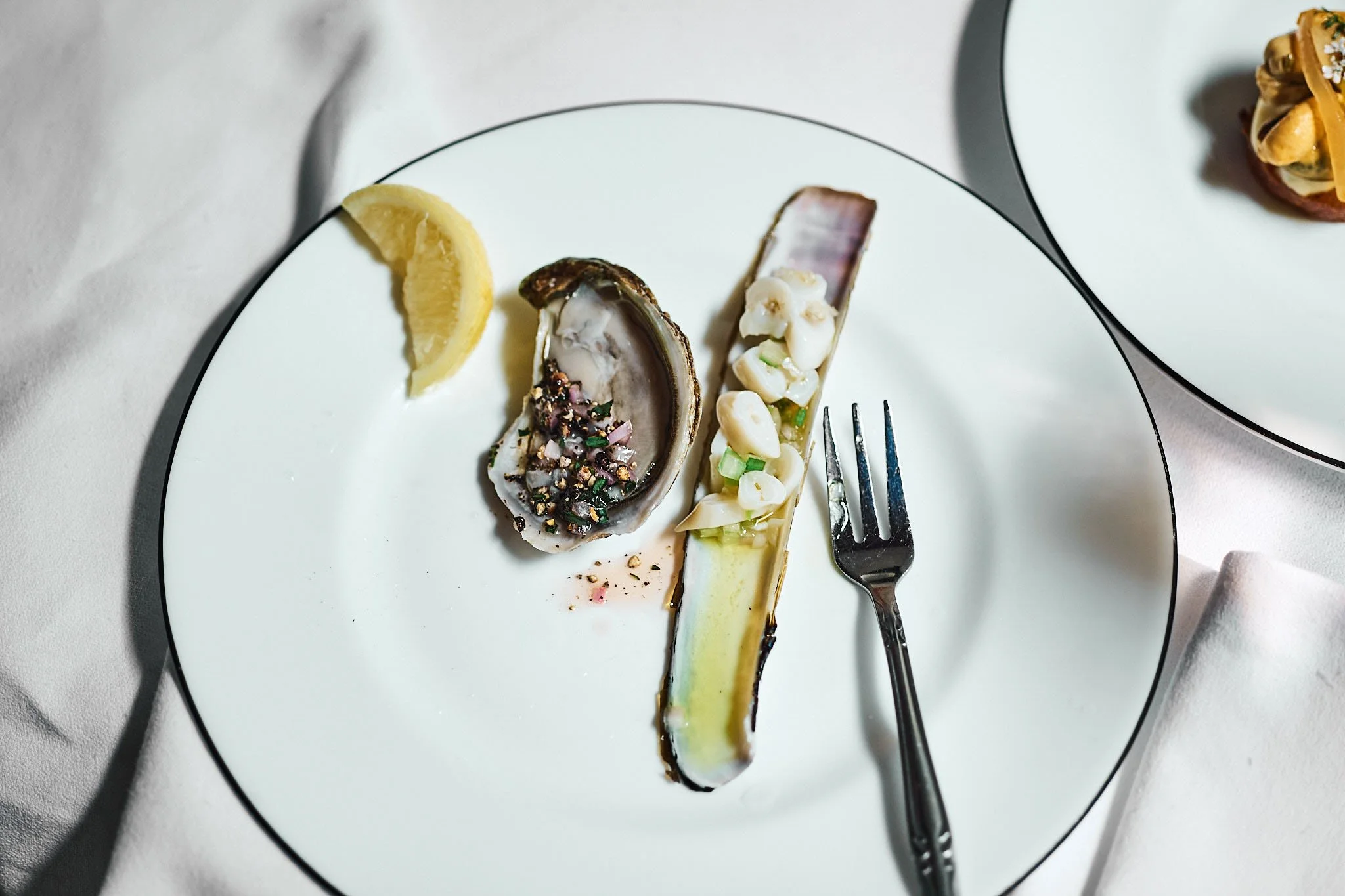 Oyster with lemon on a white plate, food photography by Oivind Haug