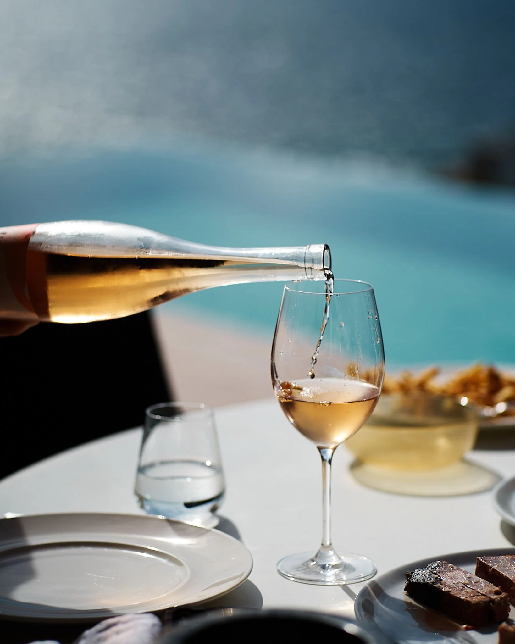Wine being poured at a table by the sea