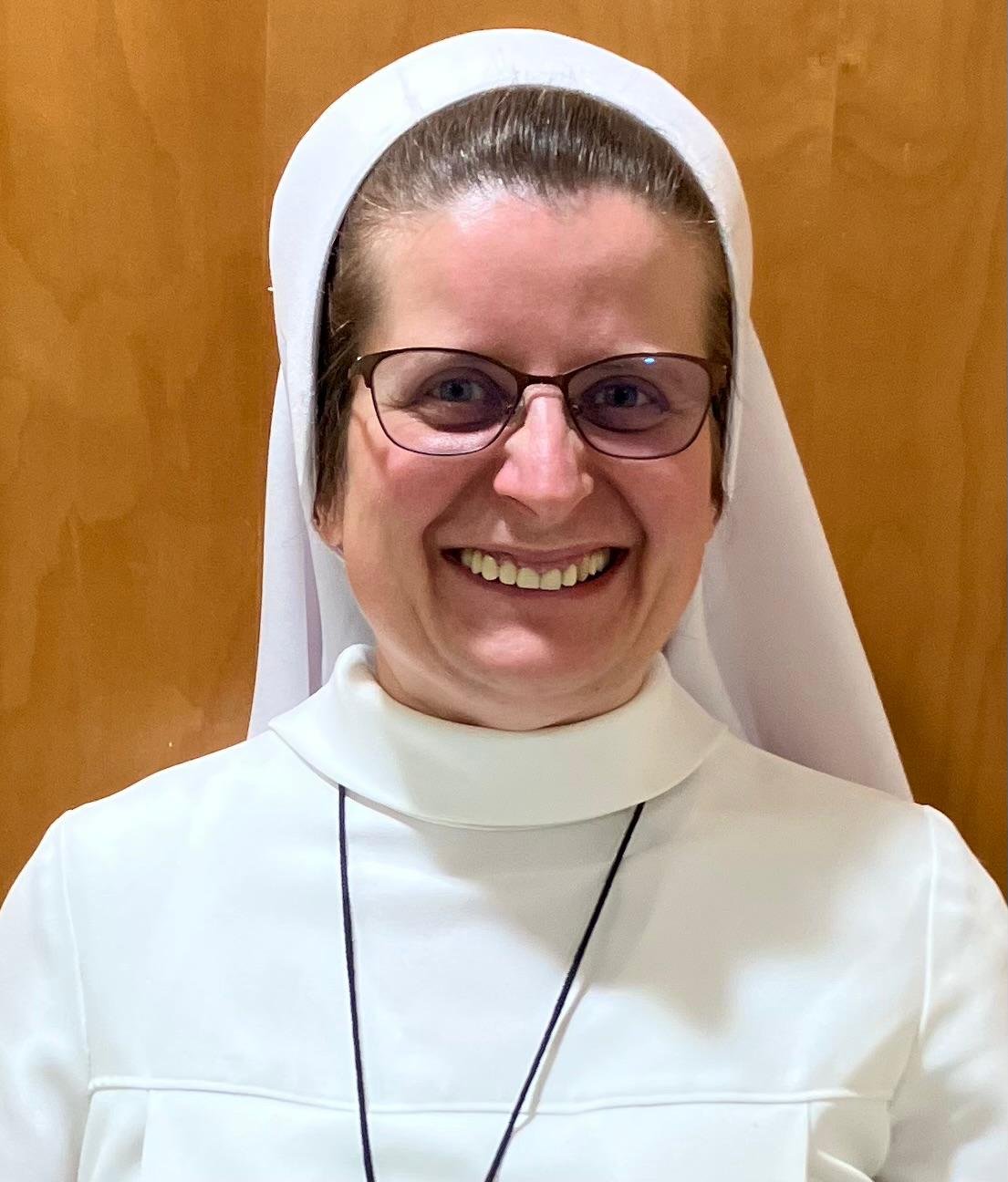 Headshot of middle age nun smiling at camera wearing glasses