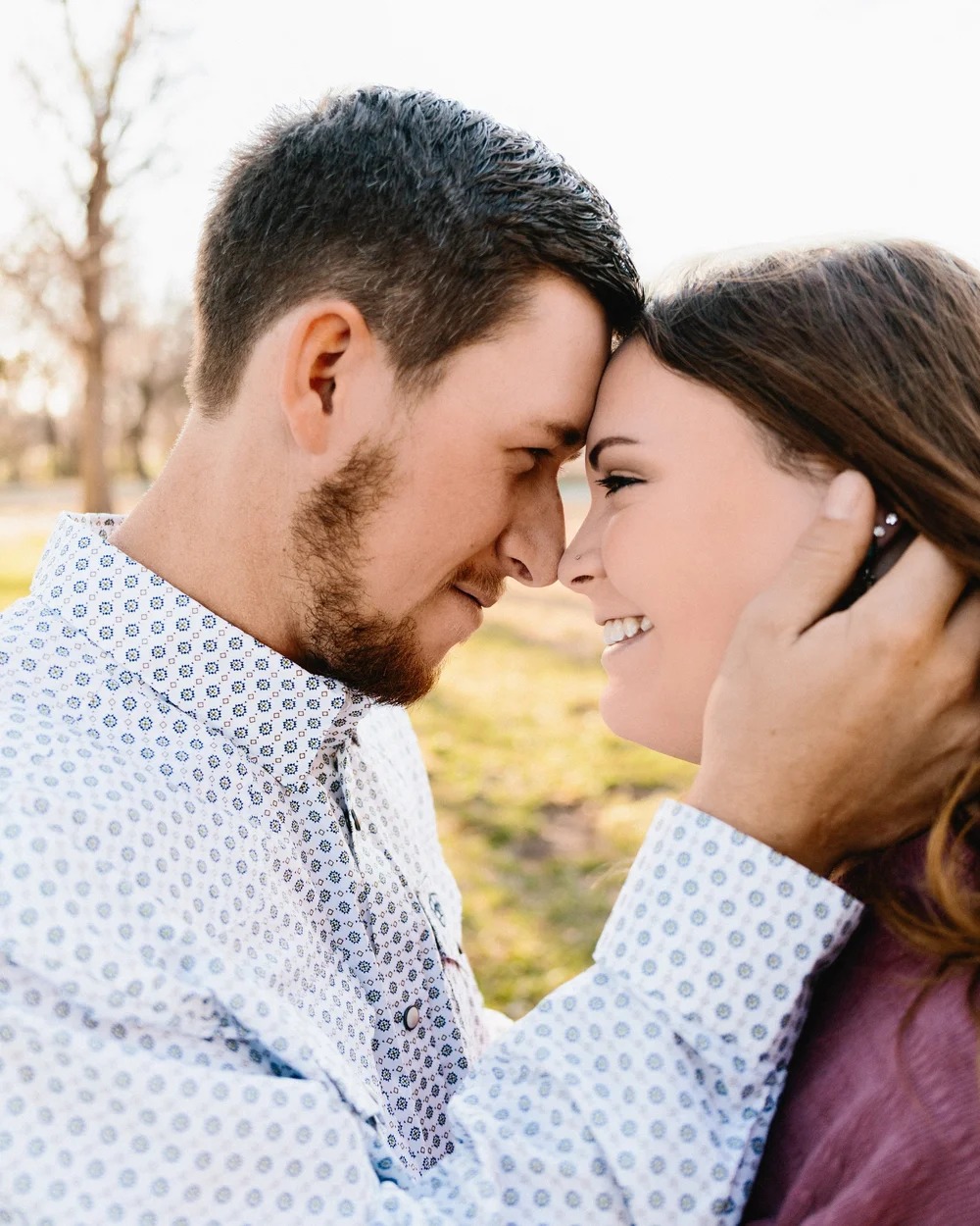 A couple touching foreheads and smiling outdoors