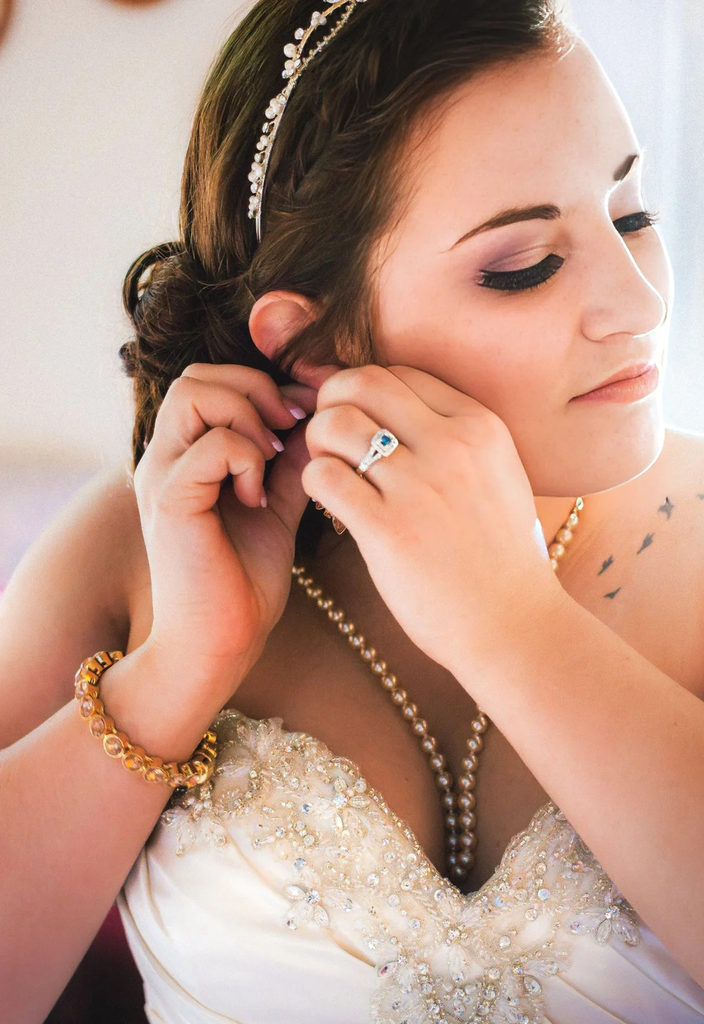 Bride putting on an earring, wearing pearls