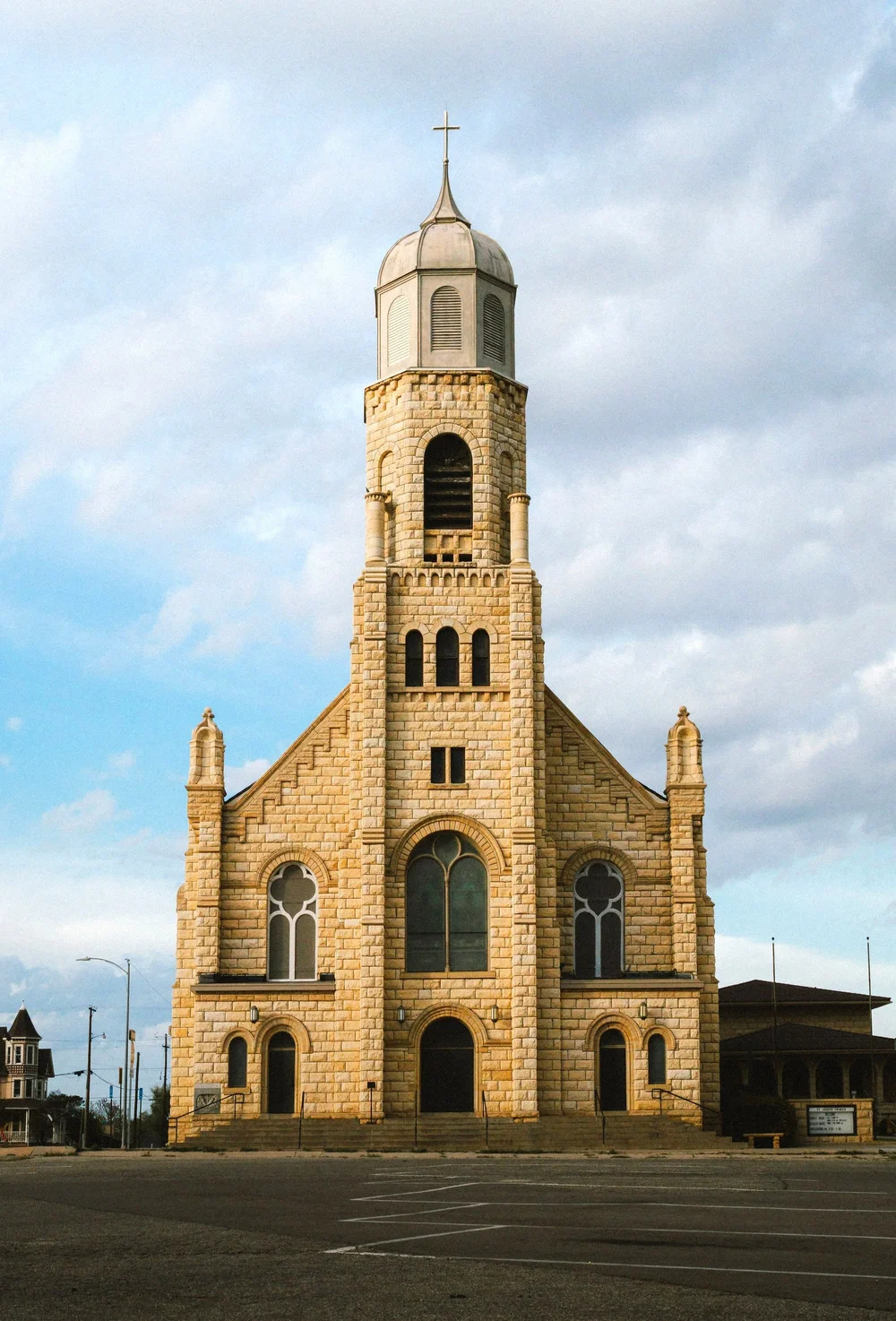 A stone church with a tall steeple against a cloudy sky