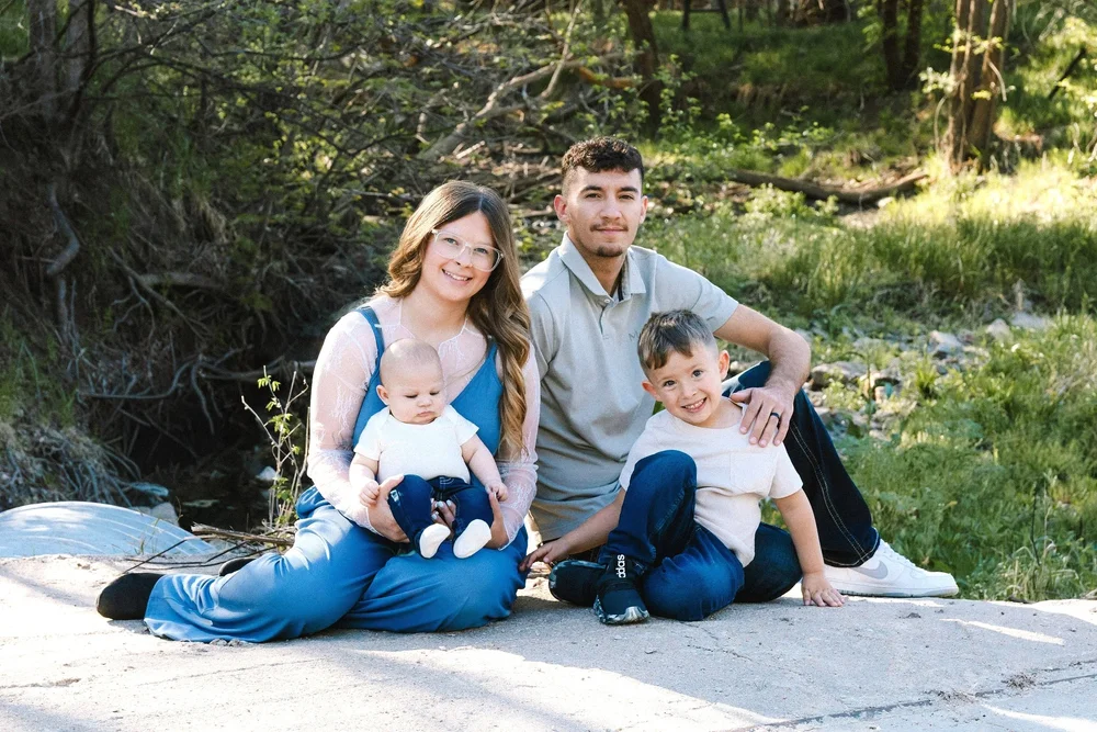 A family sitting near a creek surrounded by greenery