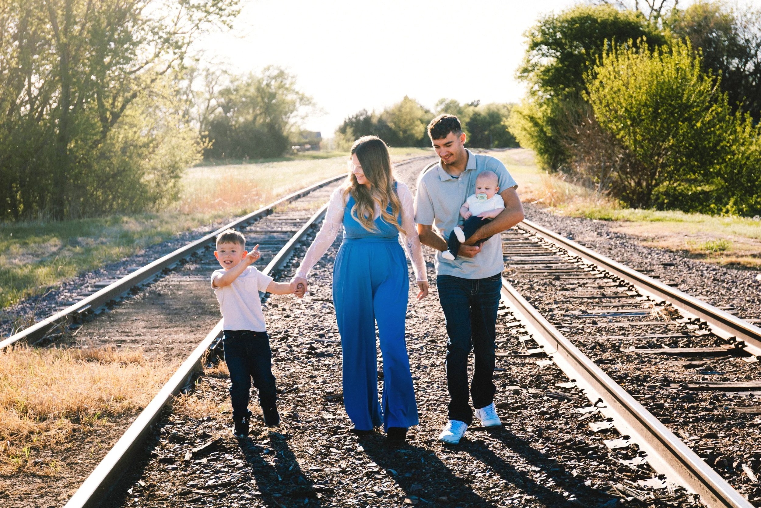 A family walking on train tracks at sunset