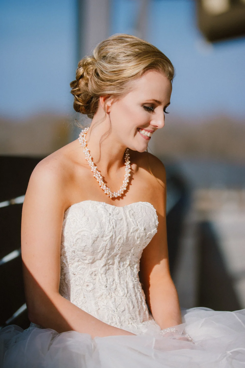 Bride in a pearl necklace smiling and looking down