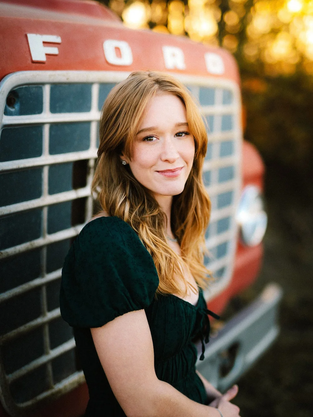 Senior portrait beside a vintage red truck in autumn light