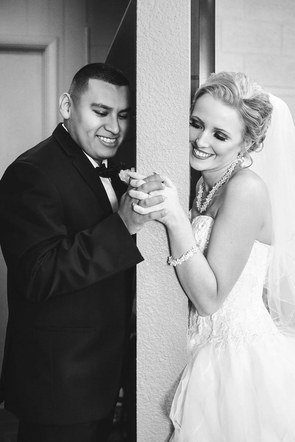 Black and white photo of a bride and groom holding hands and smiling