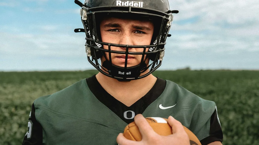 Senior football player in a field holding a football