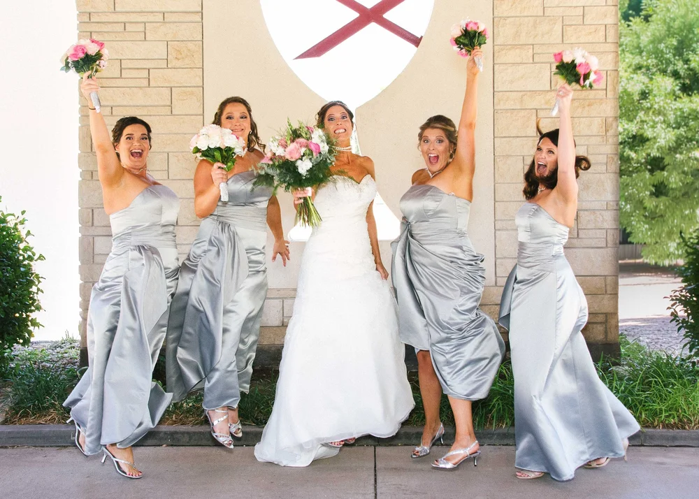 Bride with bridesmaids in front of a stone wall with a clock
