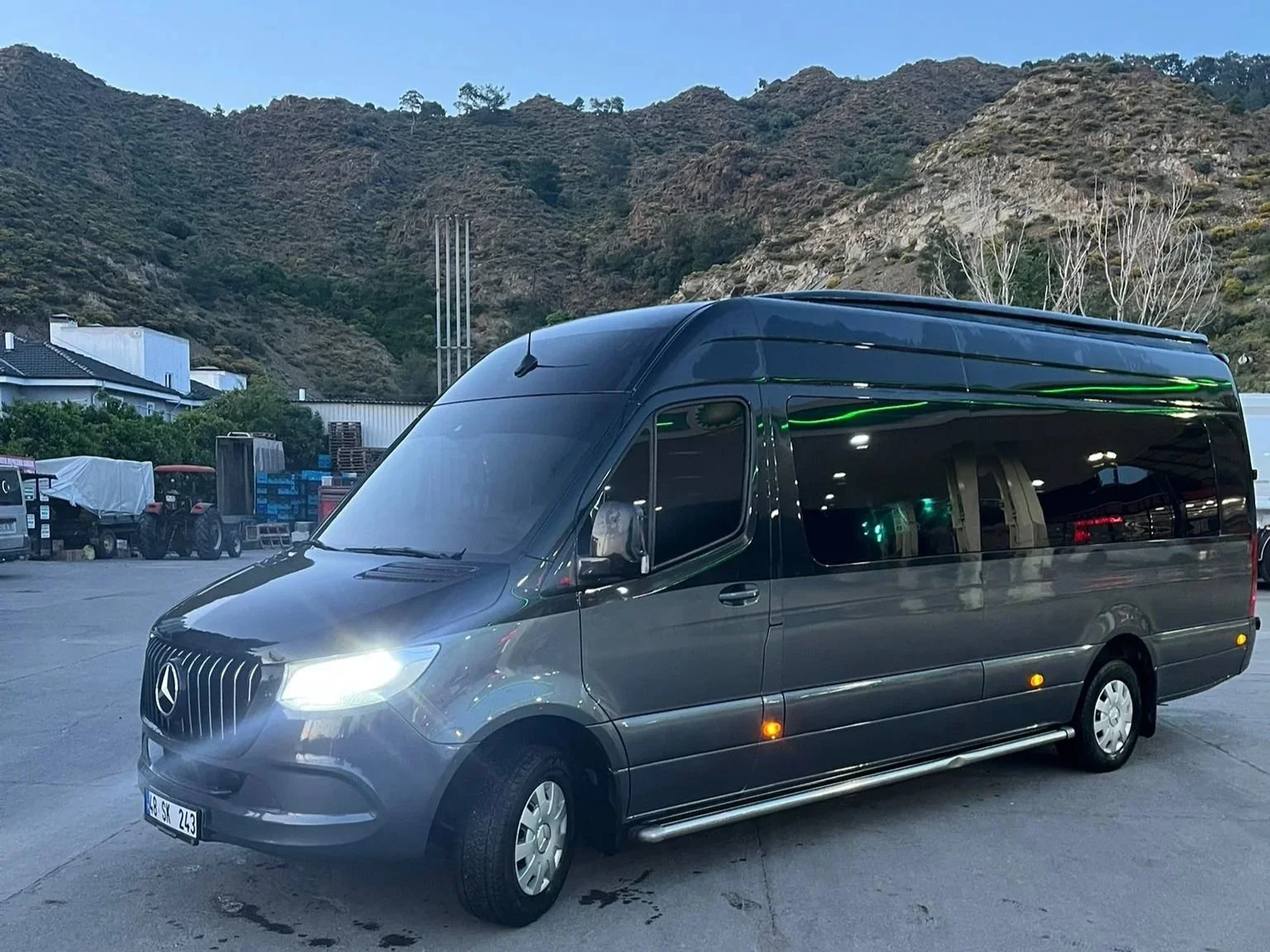 A dark gray Mercedes-Benz van parked in an outdoor area with a mountainous backdrop.