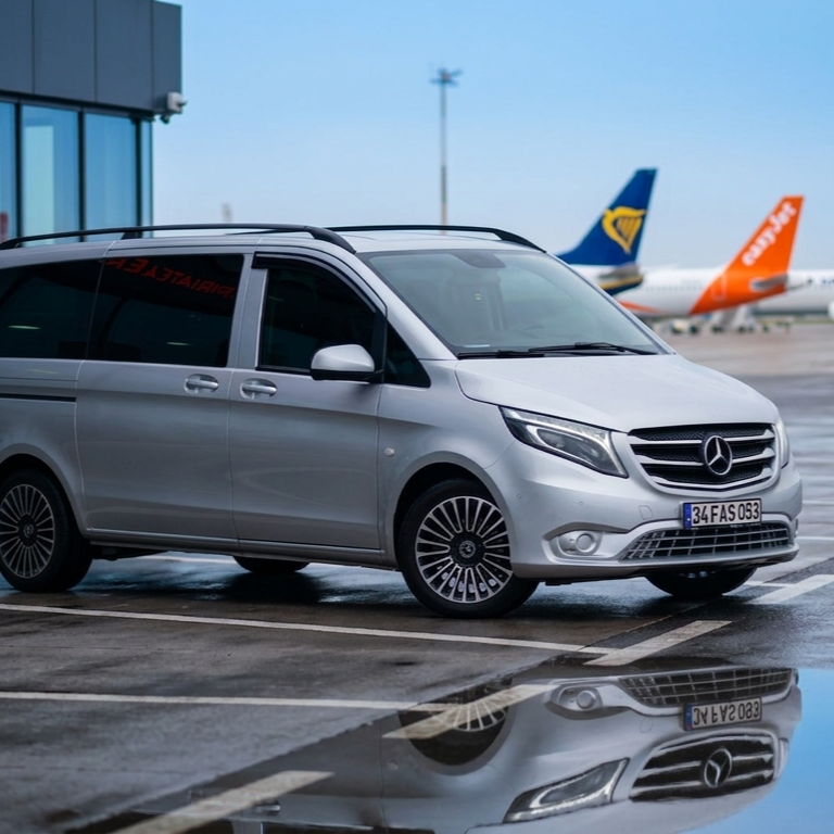 Silver Mercedes-Benz van parked at an airport, with Ryanair and EasyJet airplanes visible in the background.