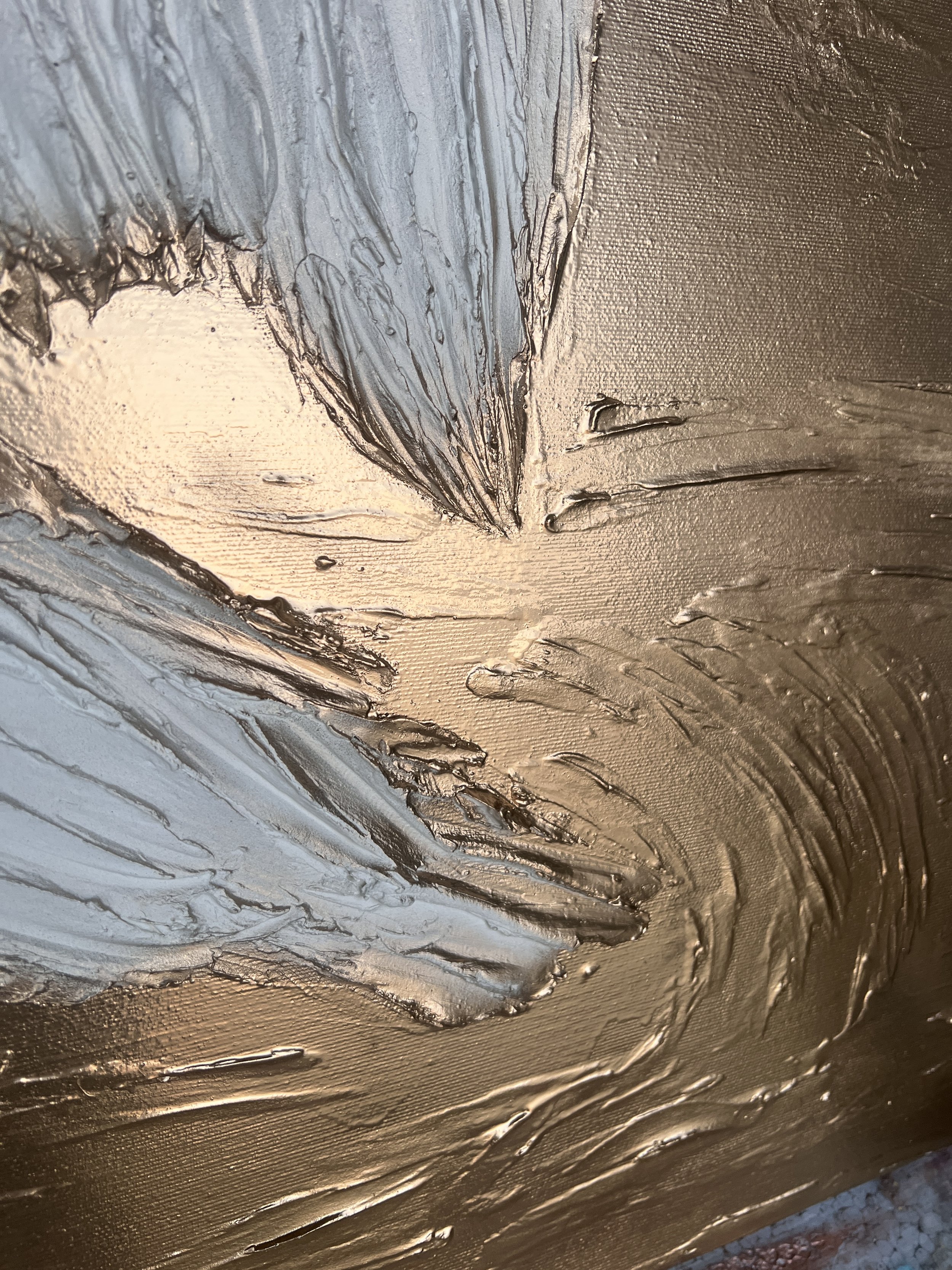 Close-up of textured metallic paint with blue and metallic gold colors, showing brush strokes and thick layers.