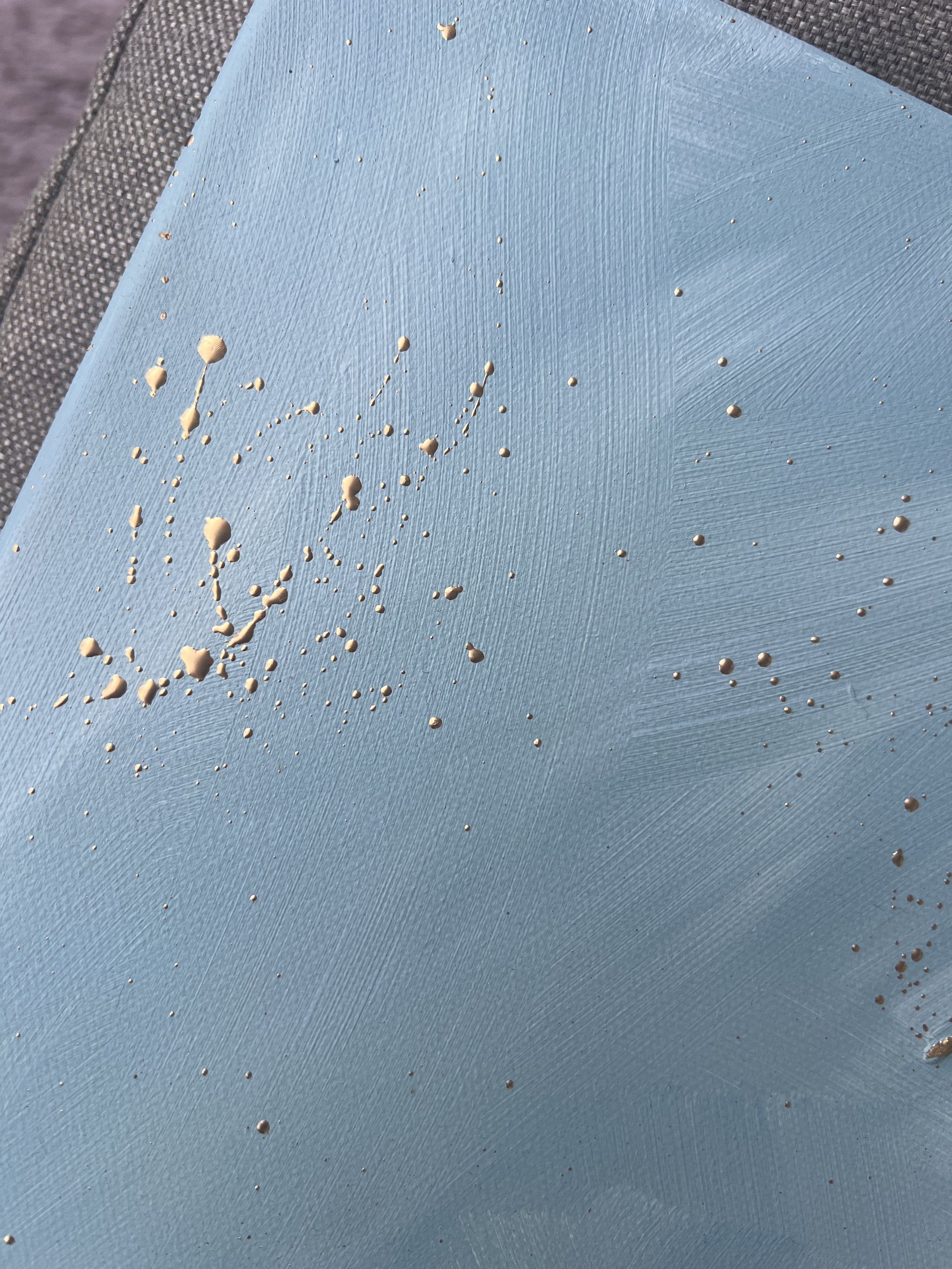 Blue canvas with white paint splatters and spots.