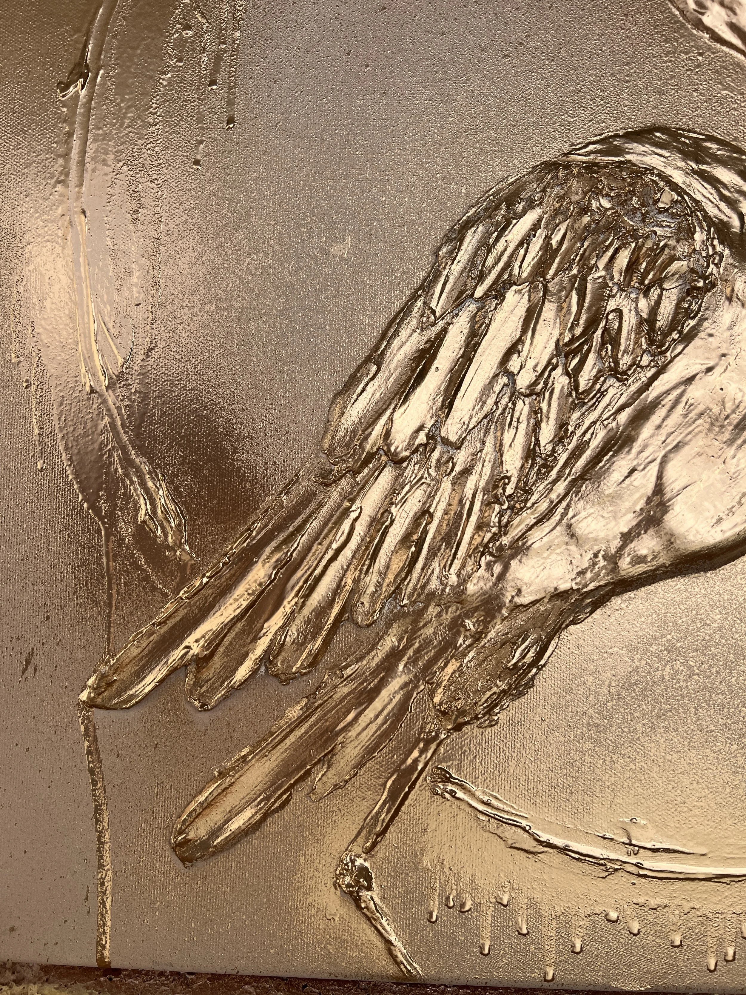 Close-up image of a metallic, textured artwork depicting a bird with outstretched wings, crafted with raised, textured metal on a smooth, metallic background.