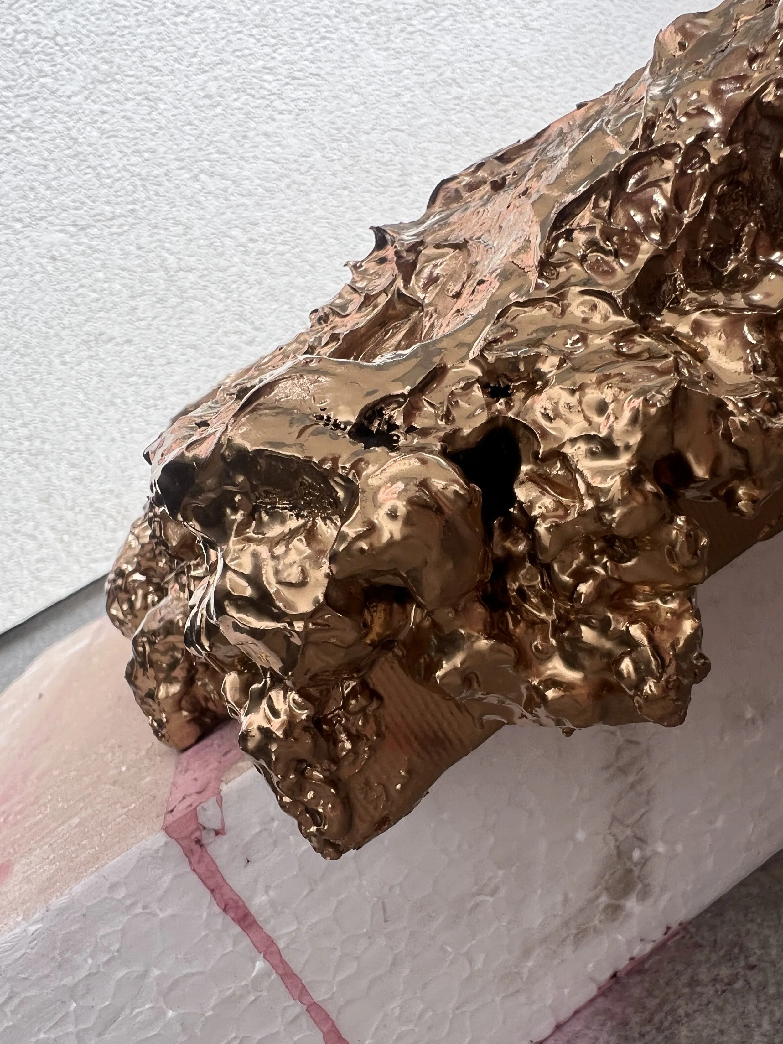 Bronzově zbarvená reliéfní malba, umístěná na obdélníkovém podstavci, s texturovaným, abstraktním stylem a lesklým povrchem, ve stylu fine art. Ideální pro milovníky moderního umění, sochařských a abstraktních reliéfních děl.
