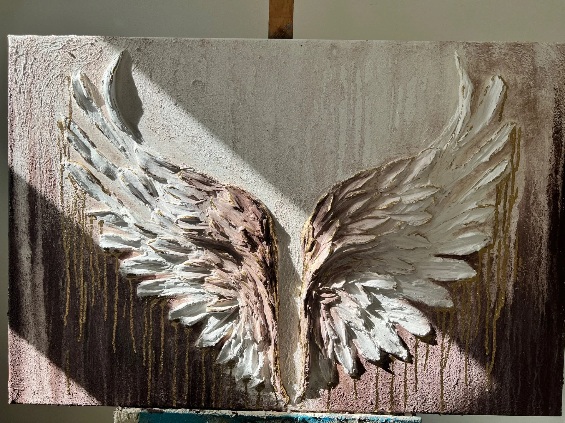 Abstract textured painting of angel wings, with gold accents and a shadow cast on the upper left.