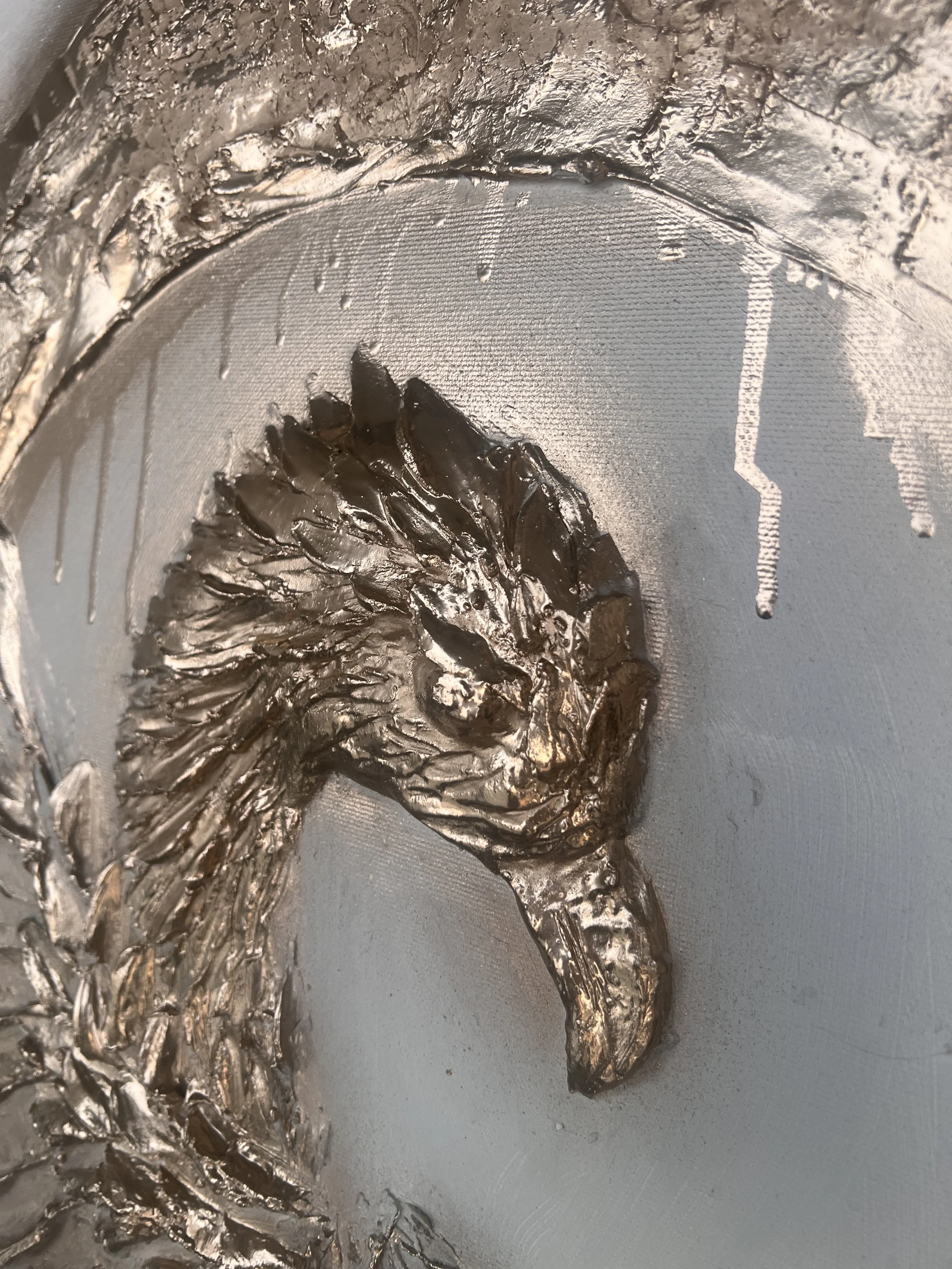 Detail reliéfní malby hlavy orla s propracovanými detaily a výrazným, dravým výrazem, ve stylu fine art. Ideální pro milovníky moderního umění, sochařských děl a texturovaných reliéfních kompozic. Strukturovaná malba Denisa Blaho
