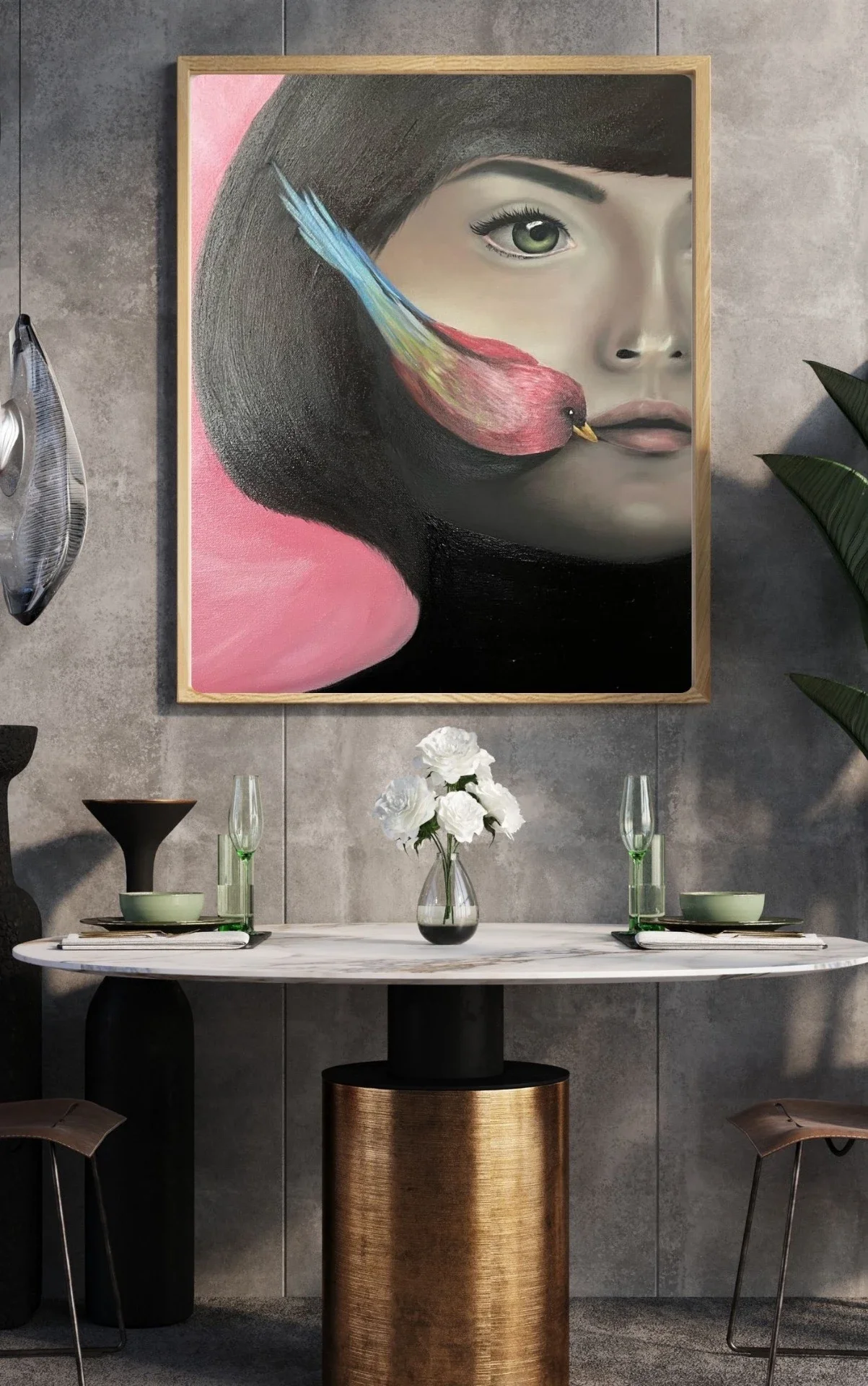 A modern dining room with a marble table, two chairs, and a contemporary painting of a woman's face with a colorful bird on her lips hanging on a gray concrete wall.