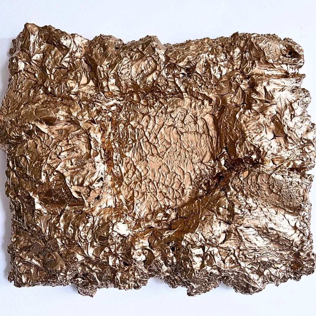 A close-up view of a crinkled, shiny, brown metallic foil square.