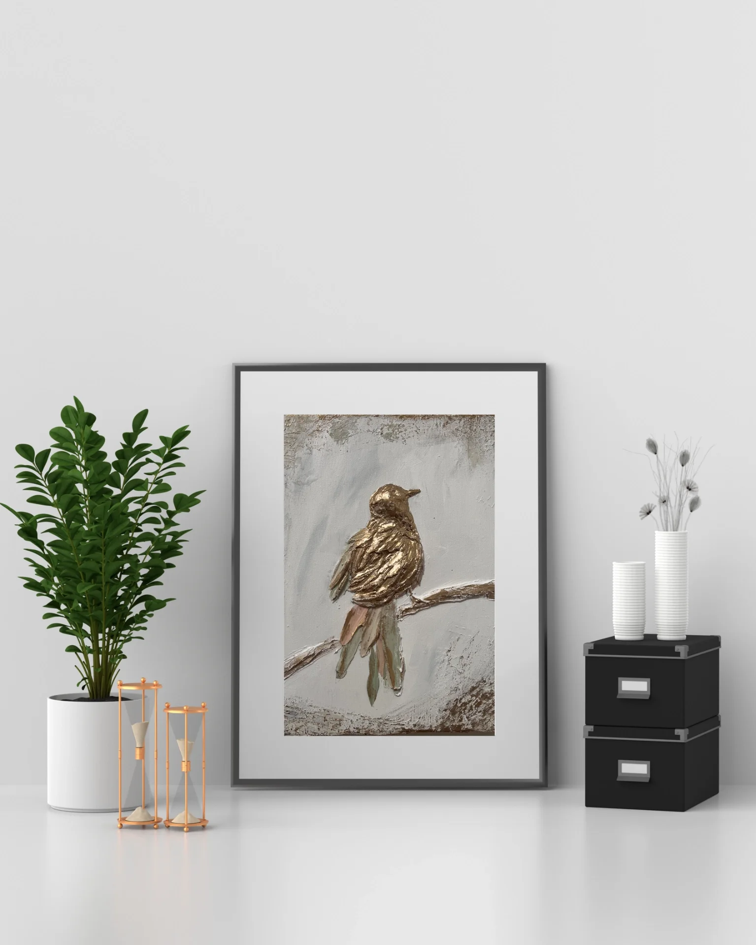 Decorative living room corner with a framed wall art of a bird, a large houseplant in a white pot, two orange hourglasses, and a black storage unit with two white vases and dried flowers.